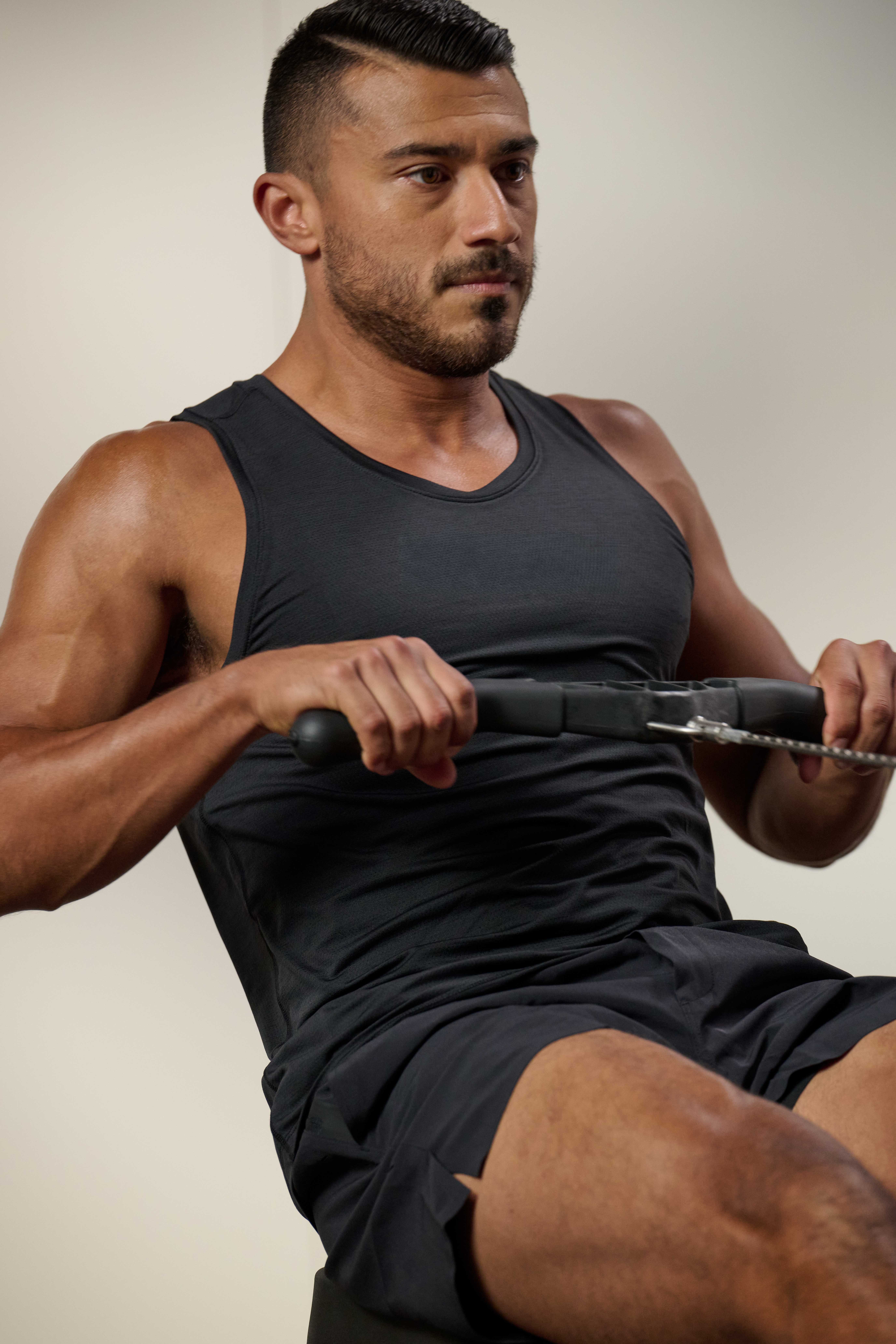 man in a black tank top using a row machine