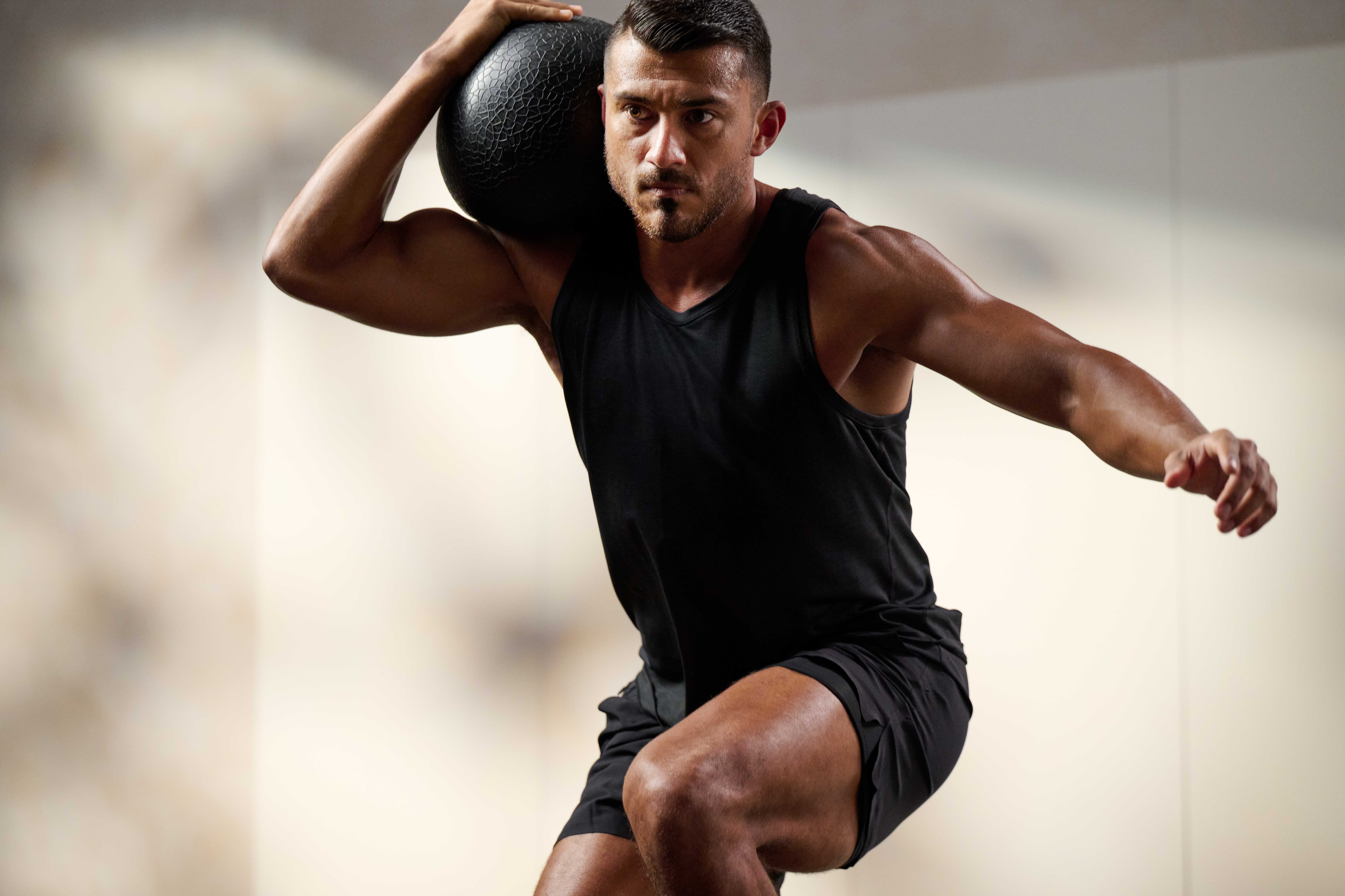 man holding a medicine ball on his shoulder