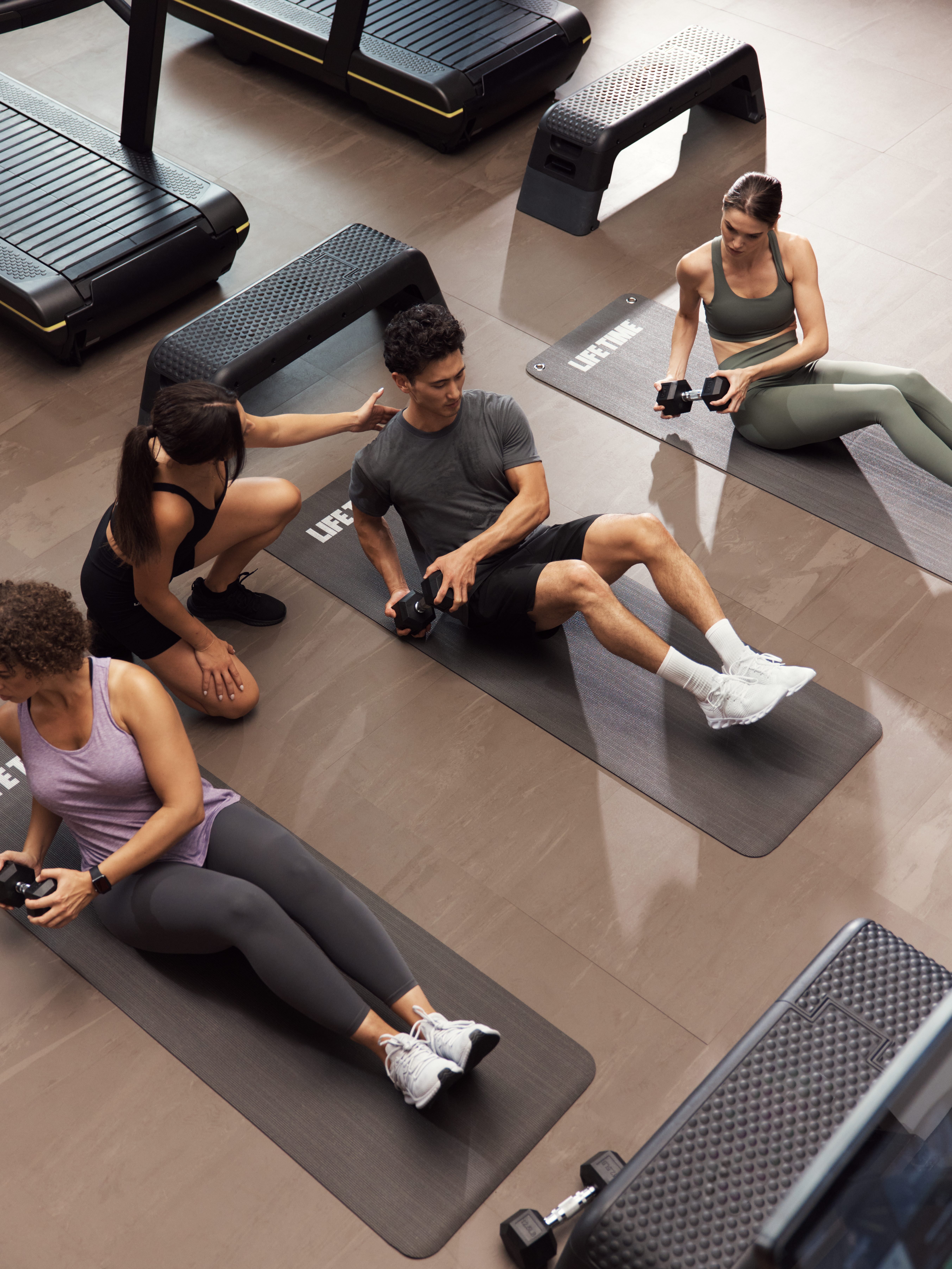 GTX boutique group training class featuring three people doing weighted Russian twists