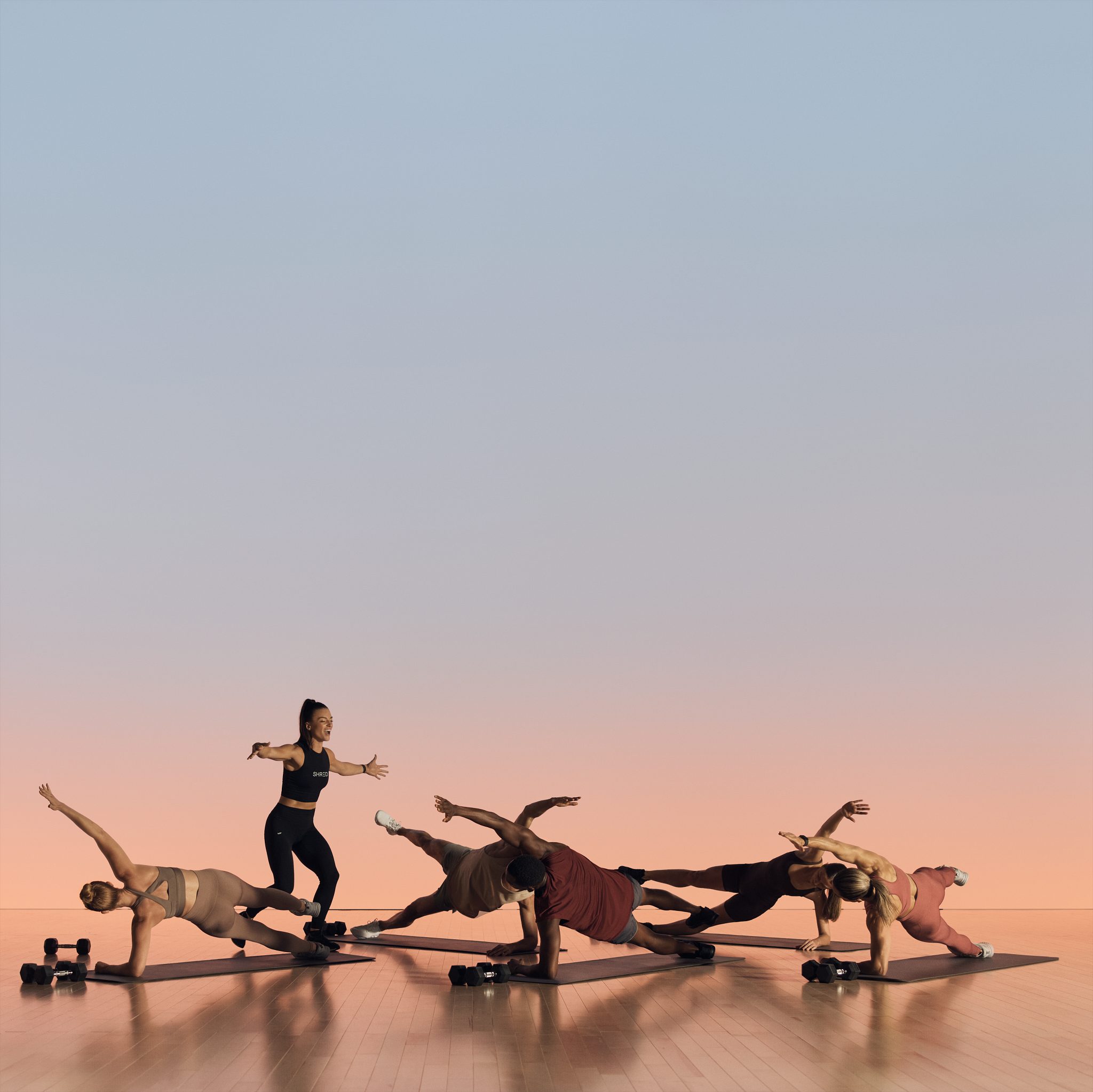 A group of Life Time members led by instructor in side plank position during a Shred strength class