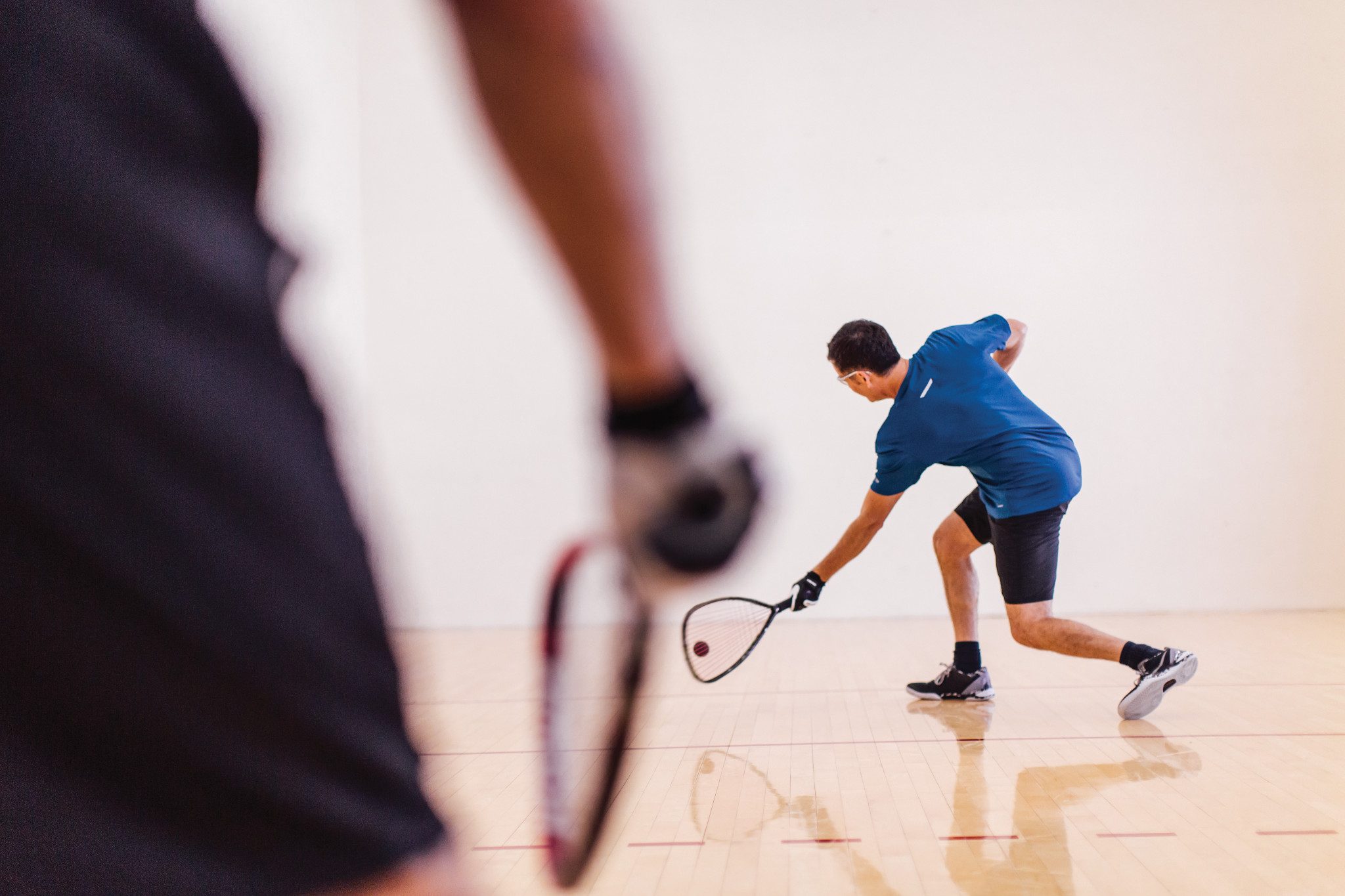 Two men playing racquetball on a racquetball court at Life Time