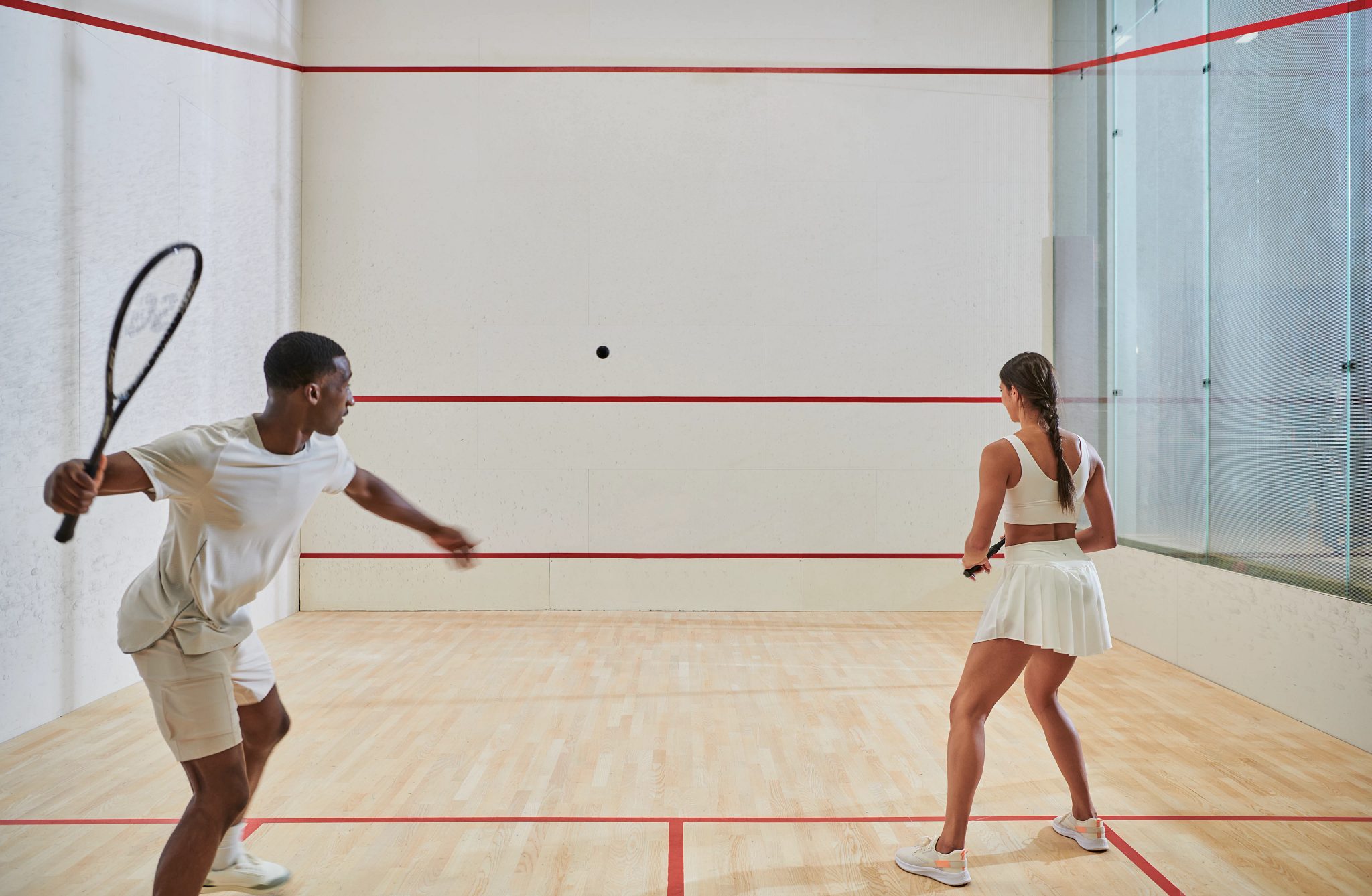A male and female couple playing a game of squash