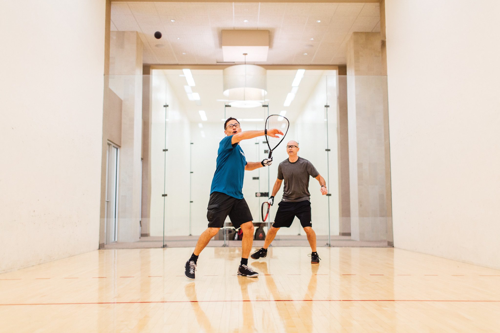 Two men playing racquetball on a racquetball court at Life Time