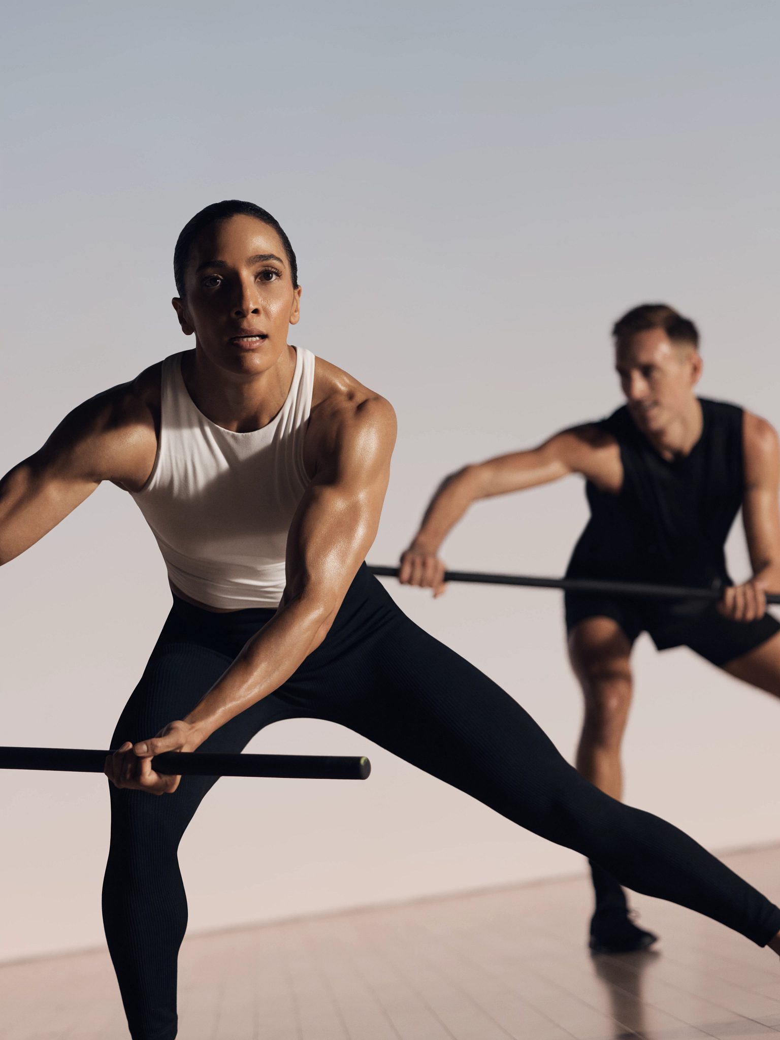 Two strike kickboxing martial arts class participants with body bars in side lunge position at Life Time
