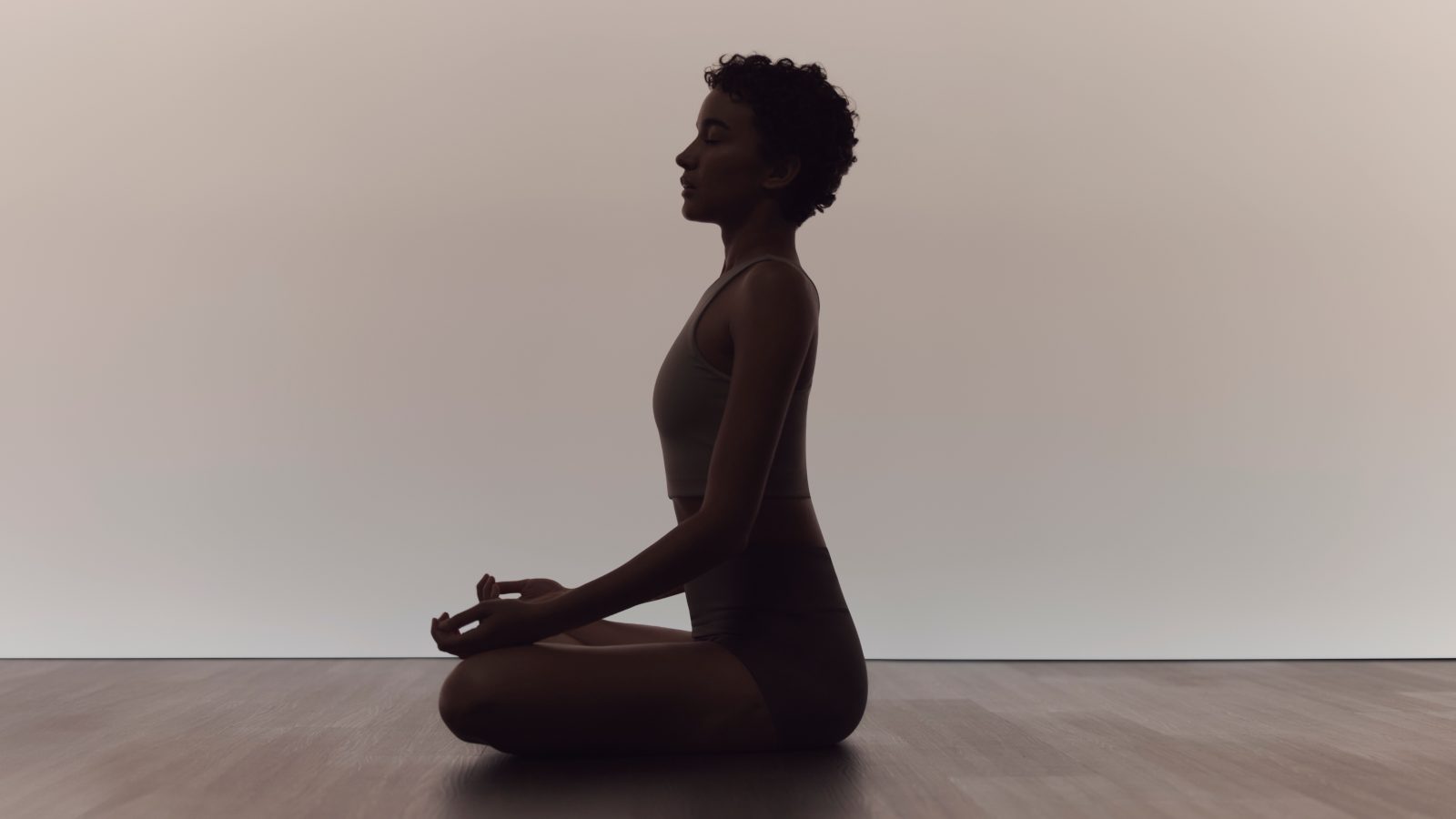Woman in calm seated sukhasana pose during a surrender yoga class