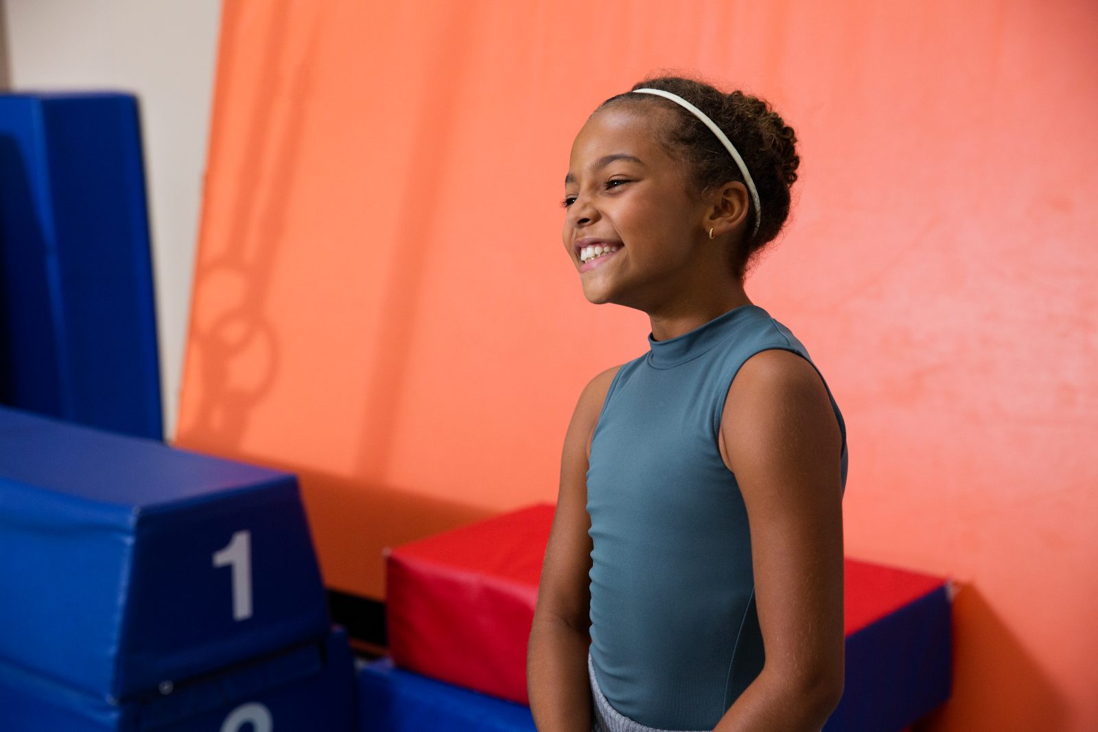 Portrait of a young girl smiling with tumbling mats behind her