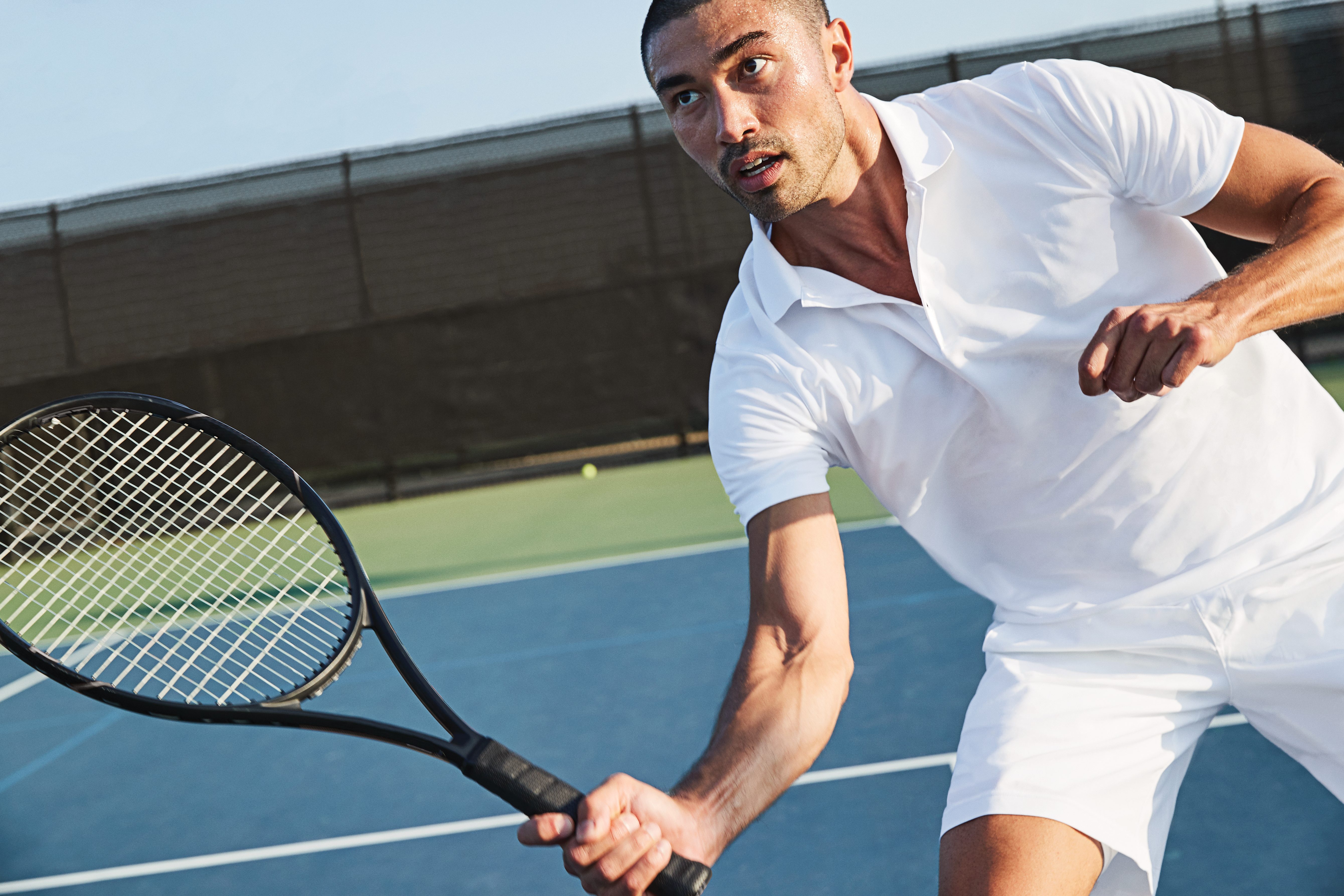 Man playing tennis on an outdoor tennis court at Life Time