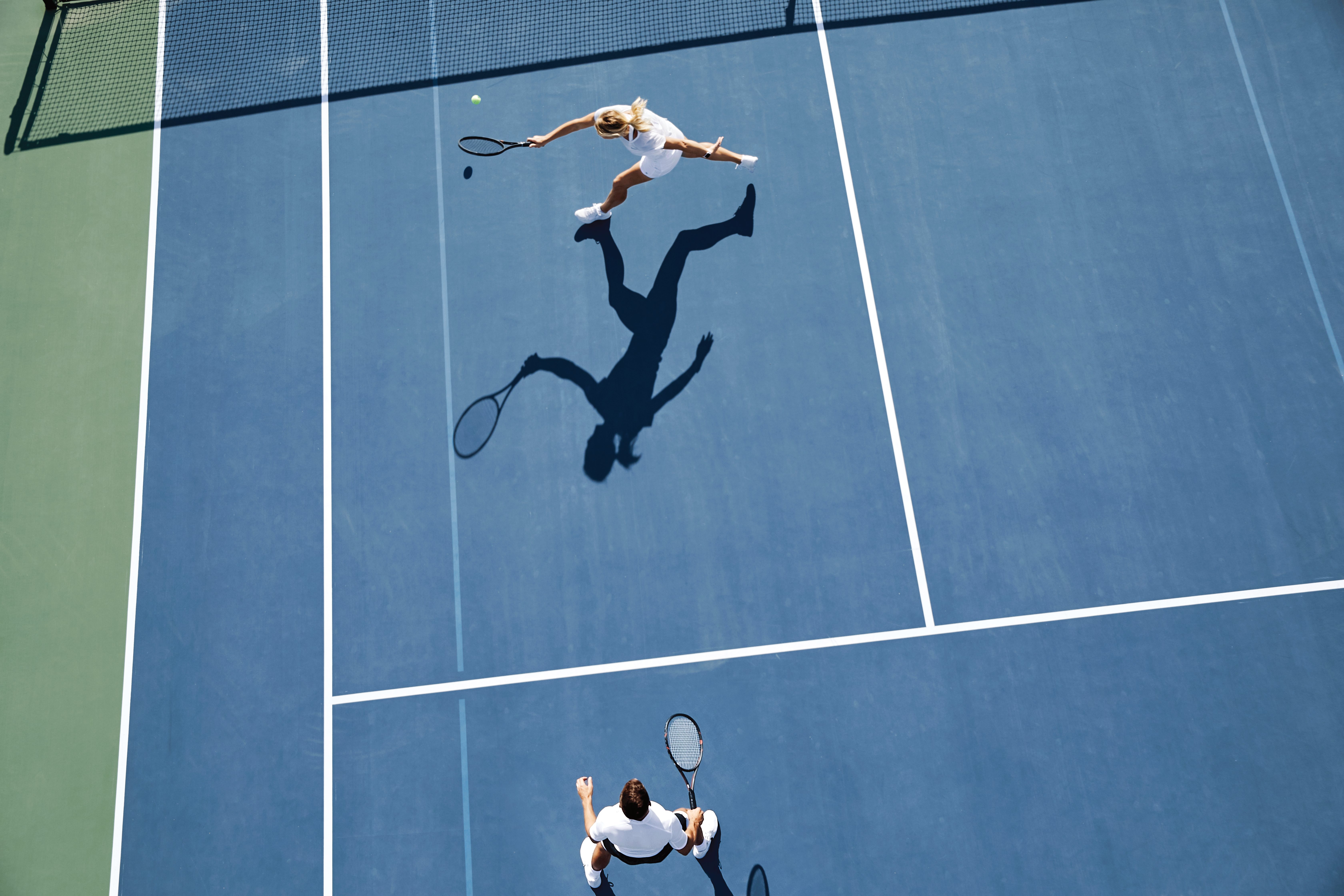 Aerial view of two people playing tennis on an outdoor tennis court