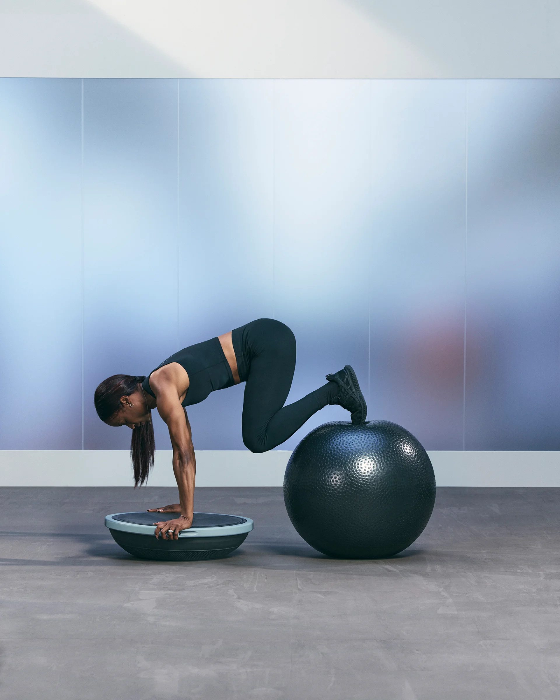 a woman doing a knee plank on a bosu ball