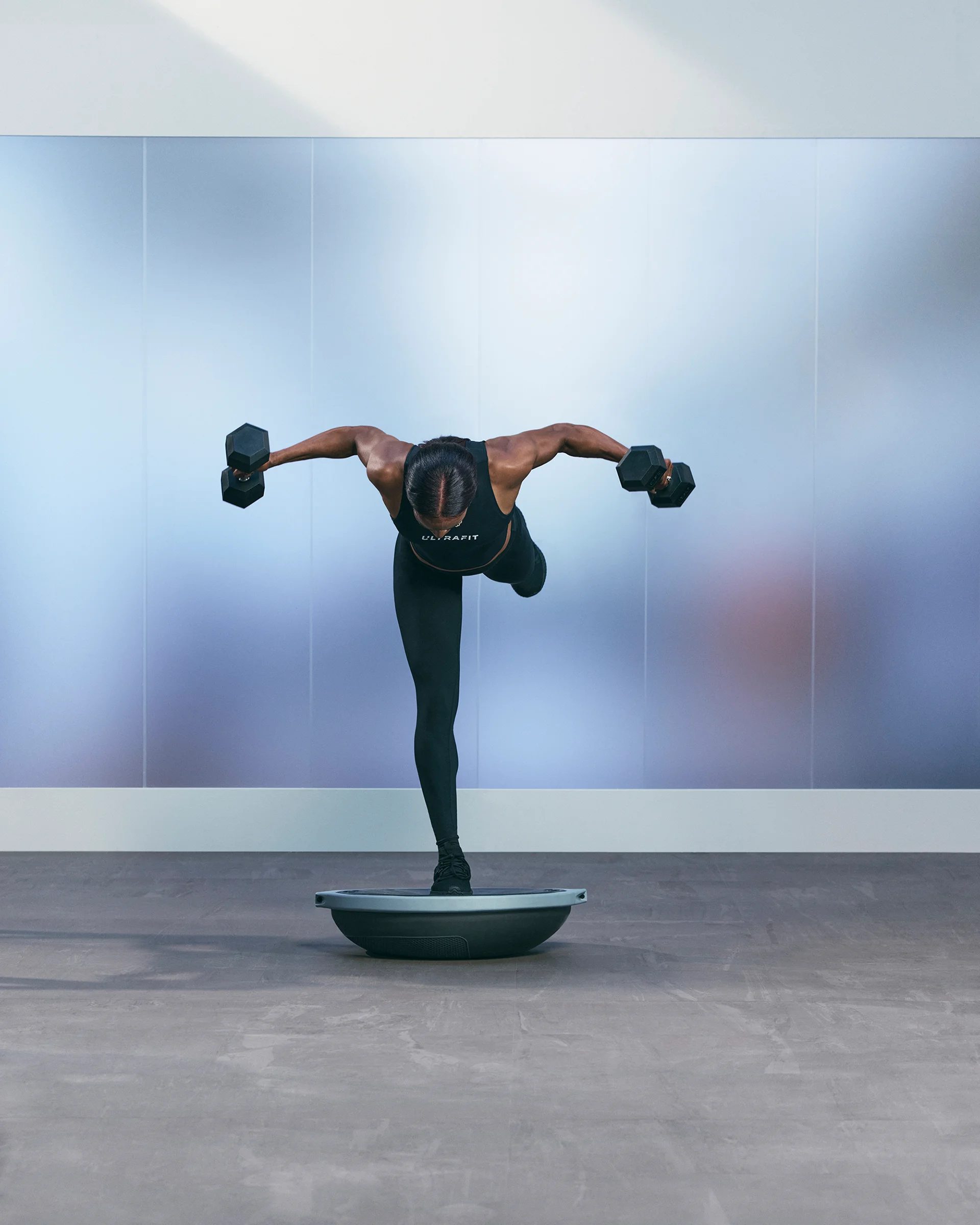 a woman doing a single leg bosu bent over fly pose