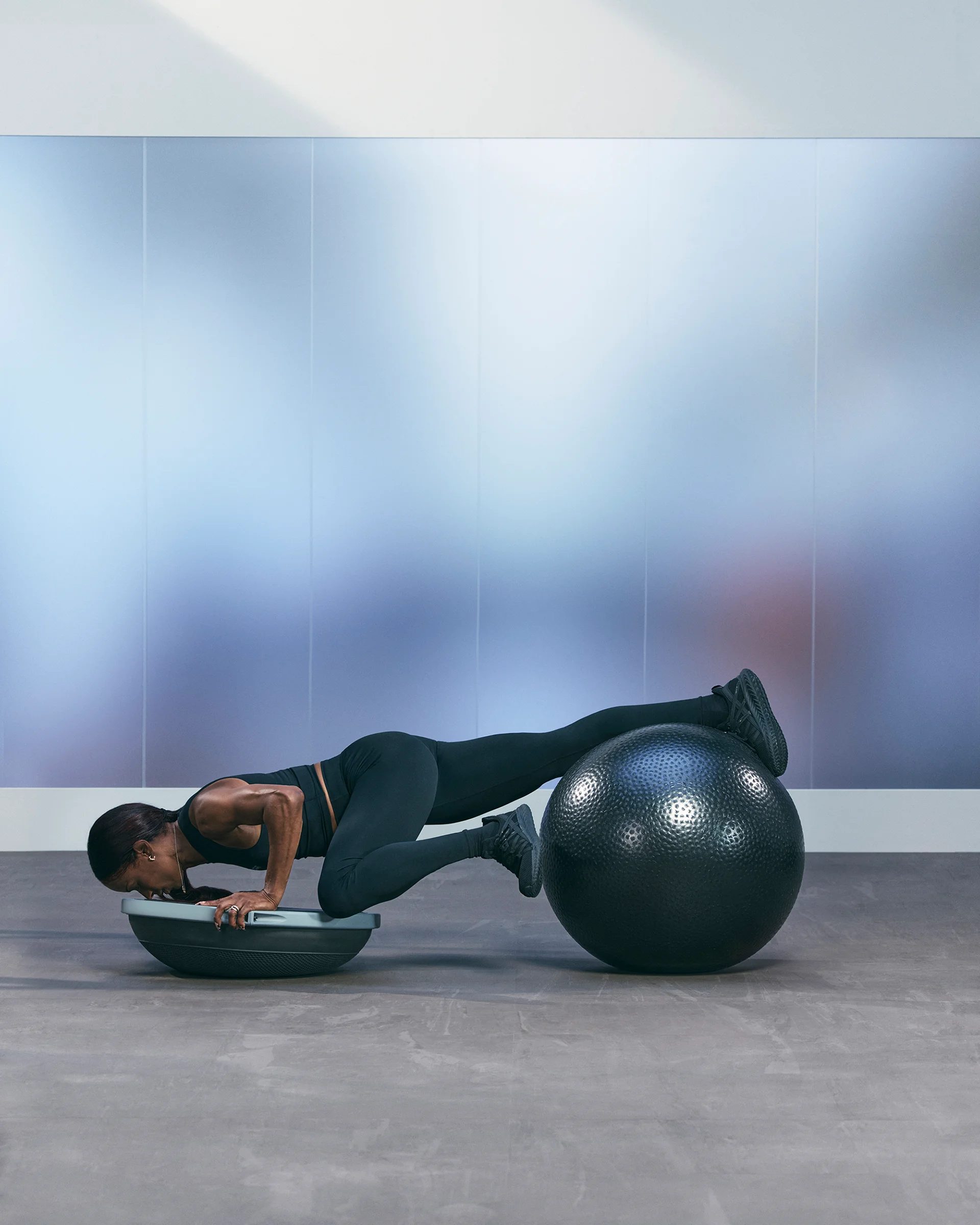 a woman doing a spiderman pushup on a bosu and stability ball