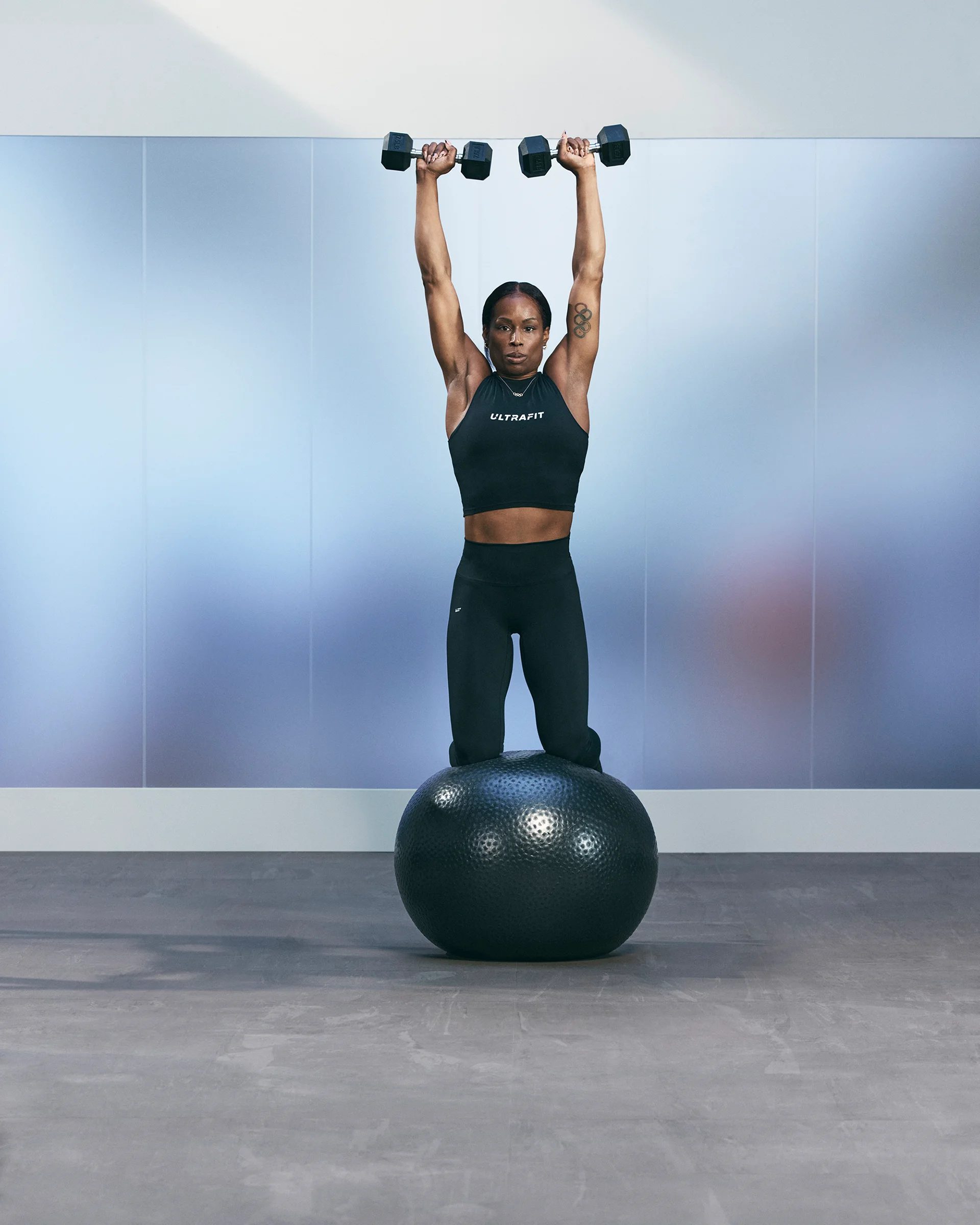 a woman doing a kneeling shoulder press on a stability ball