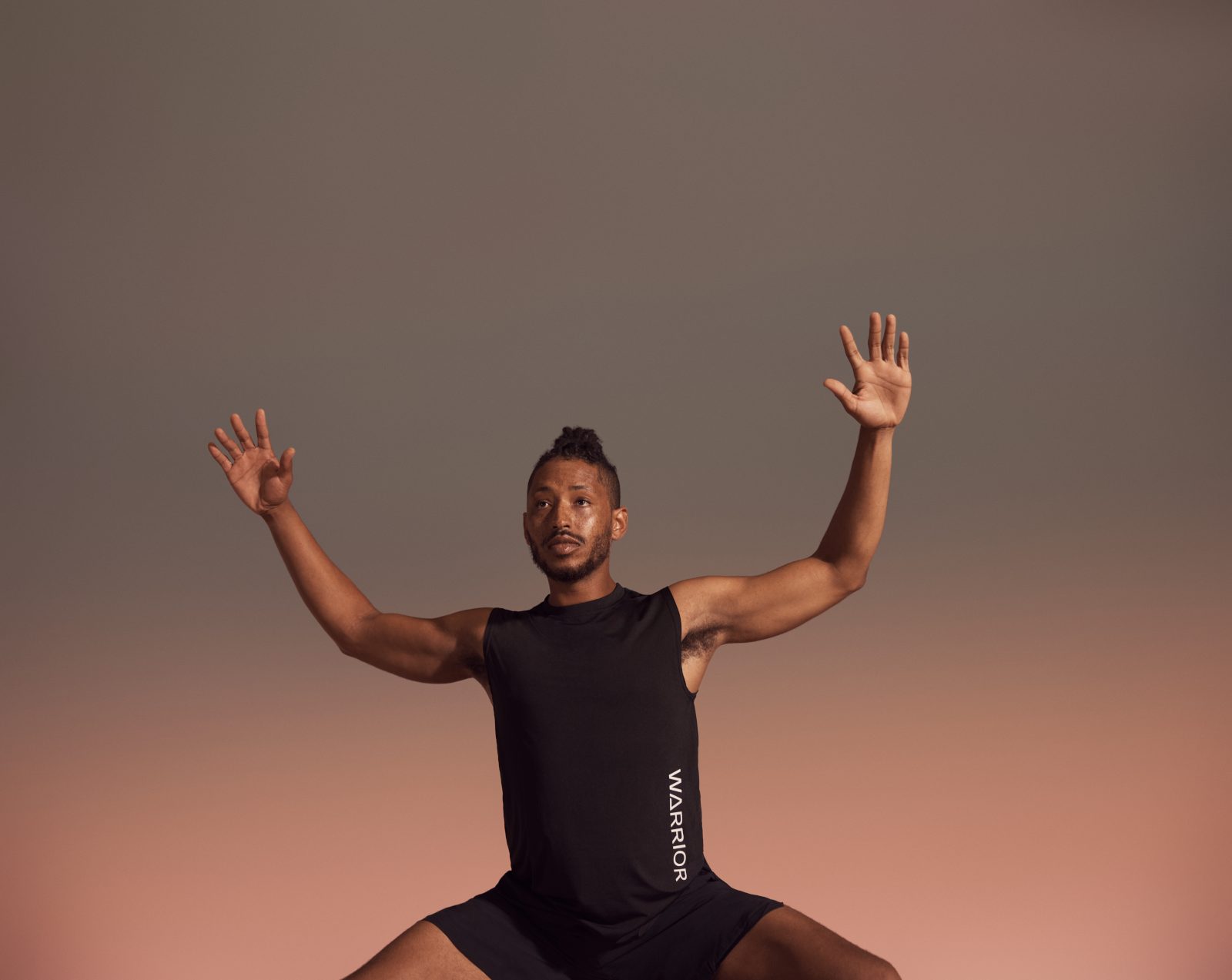 Yogi with raised arms in deep squat position during warrior sculpt class at Life Time