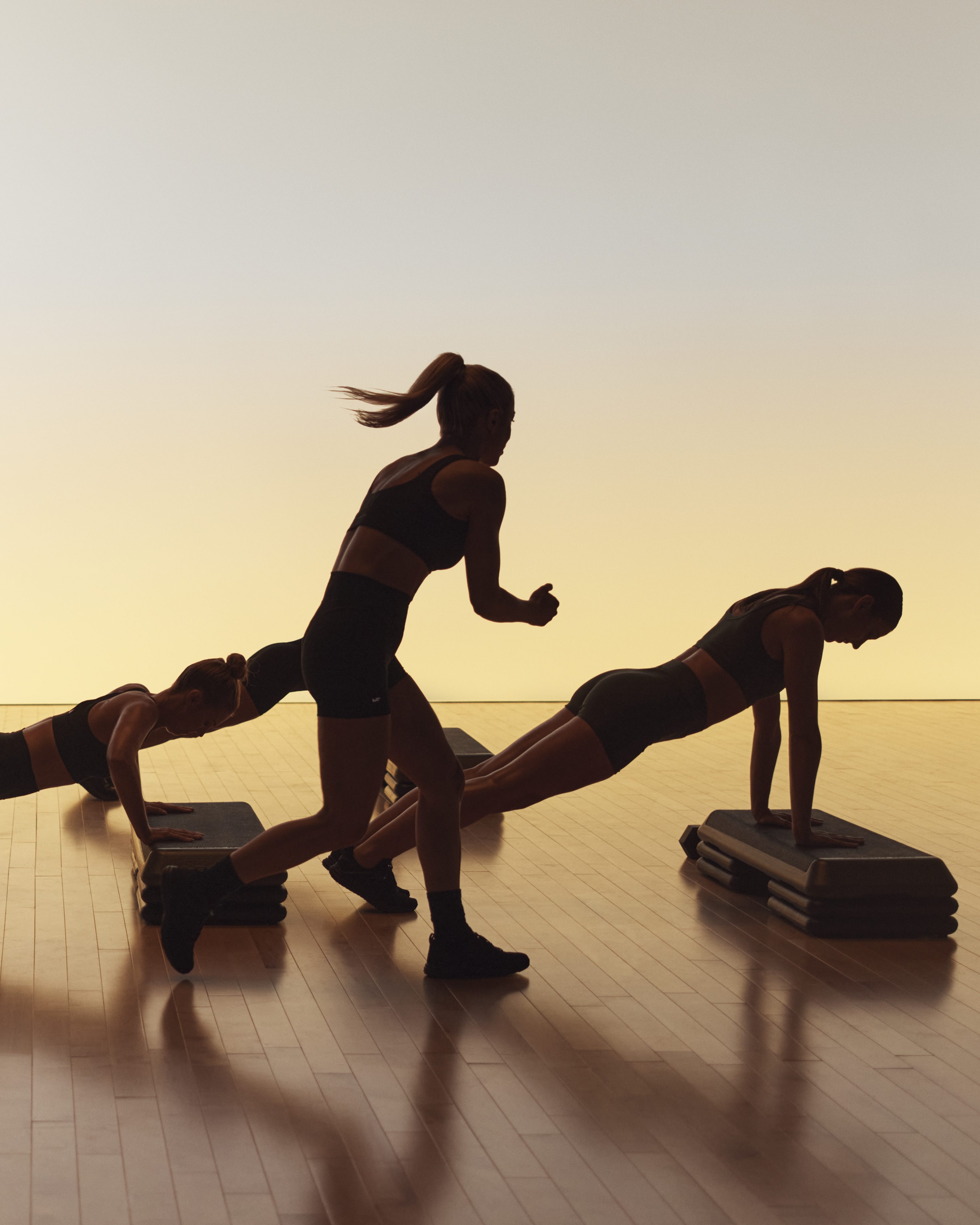 Xtreme cardio class members doing skaters and using step benches at Life Time