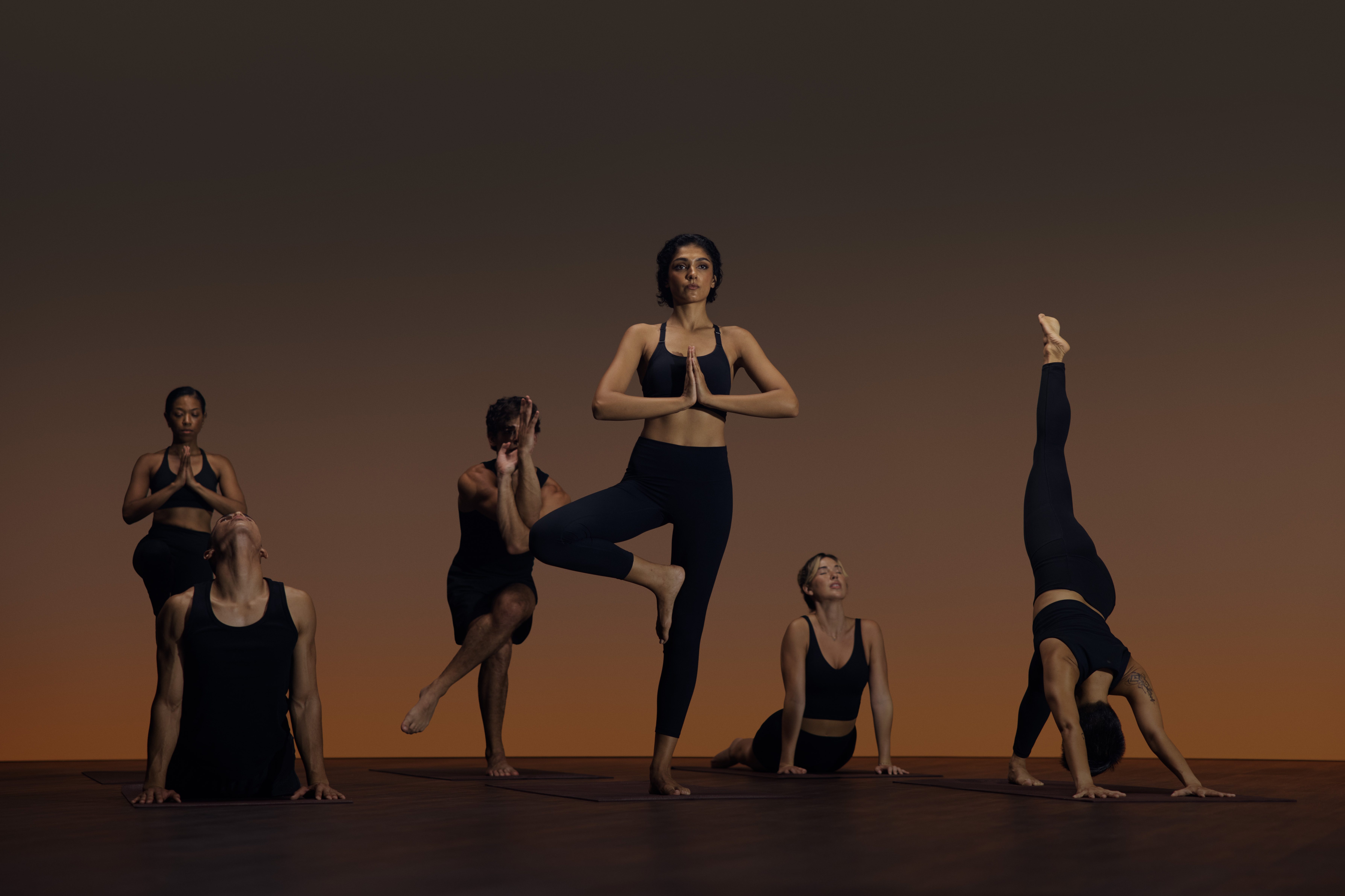 Group of six people in varying yoga poses at a flow yoga class