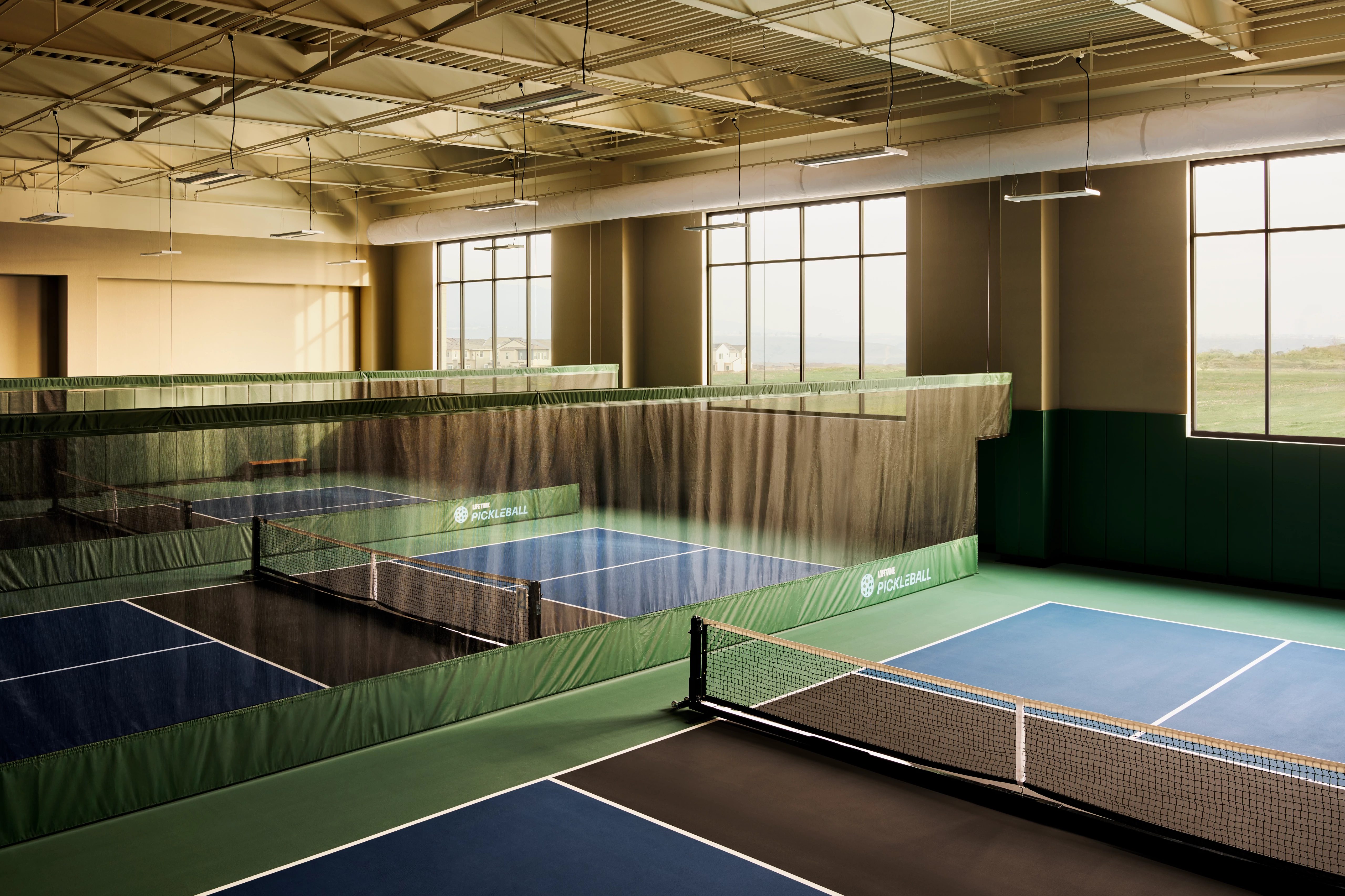 3 indoor pickleball courts in a brightly lit gymnasium