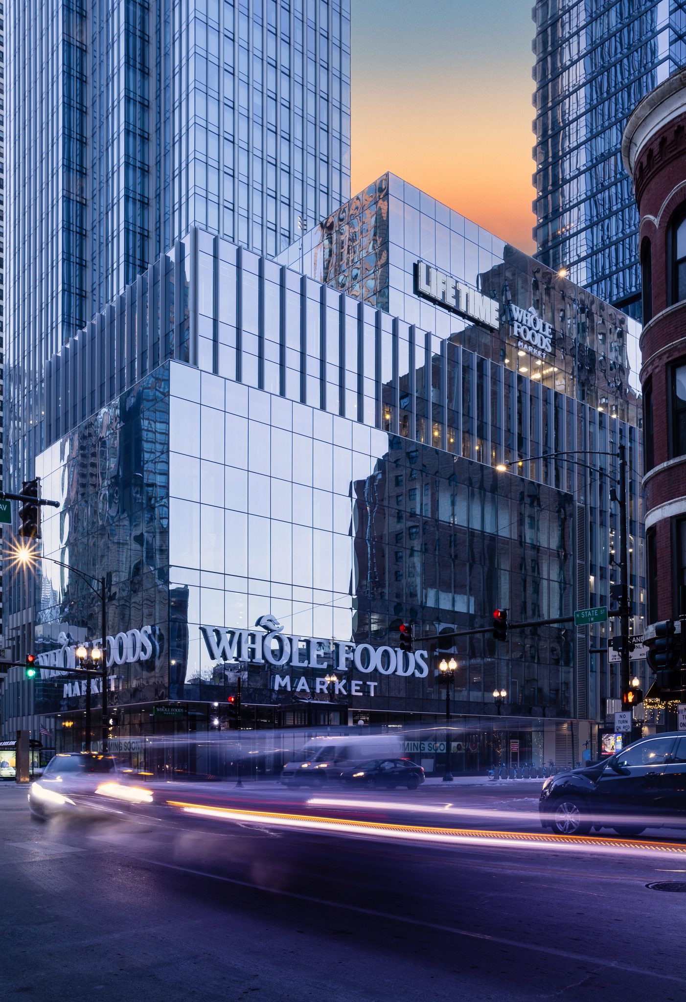 The glass exterior and busy street of Life Time River North at One Chicago at dusk