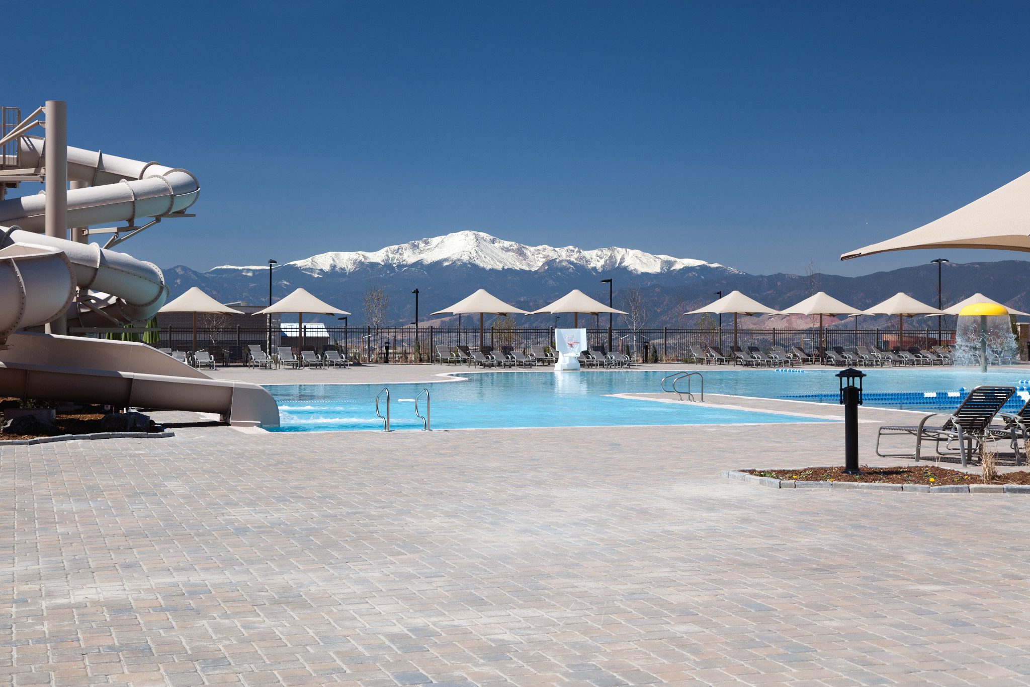 An outdoor pool with waterslides, and mountains in the background