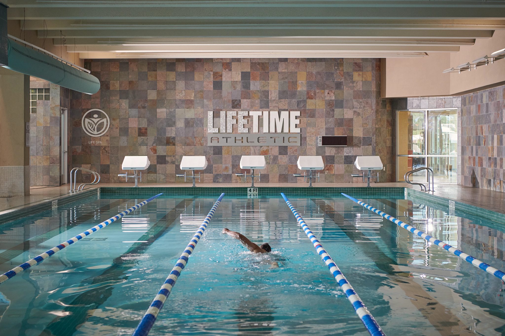 A man swimming laps in an indoor lap pool