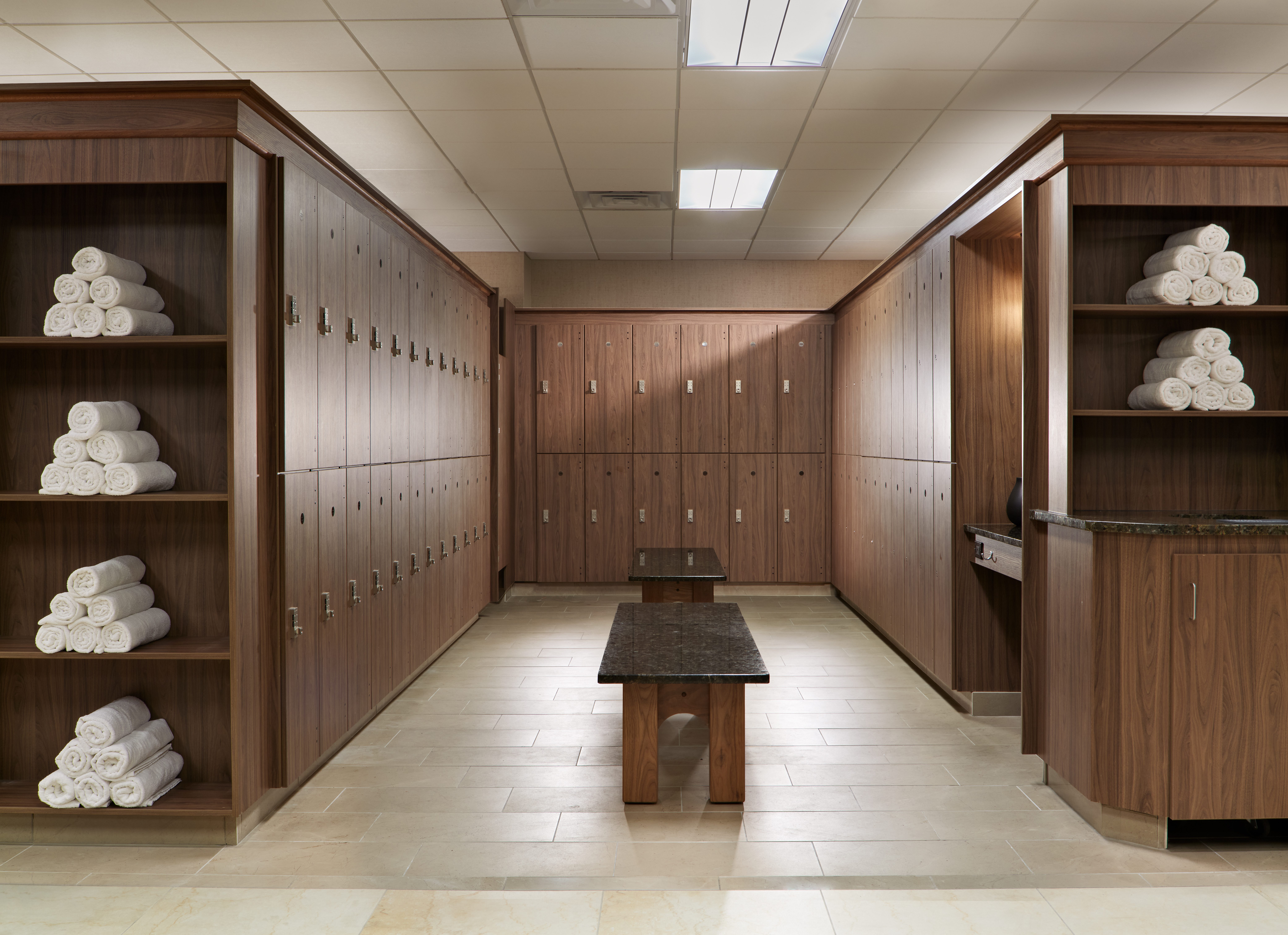 Wooden locker room bay with marble benches and rolled up towels