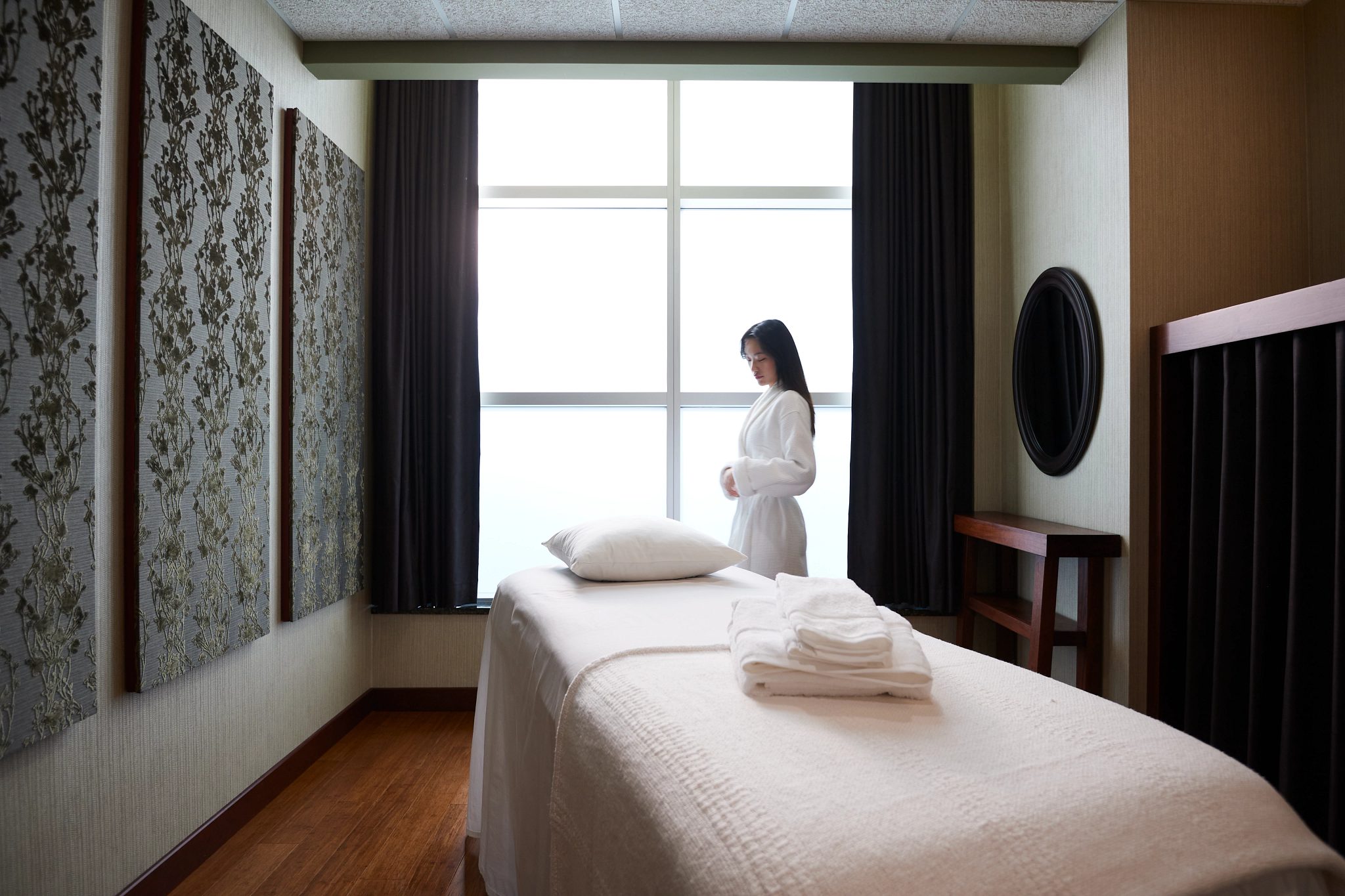 A female wearing a white robe standing next to a massage table