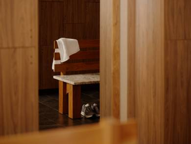 A towel and tennis shoes on a bench next to a bay of lockers in the Life Time Atlantic Avenue club location.