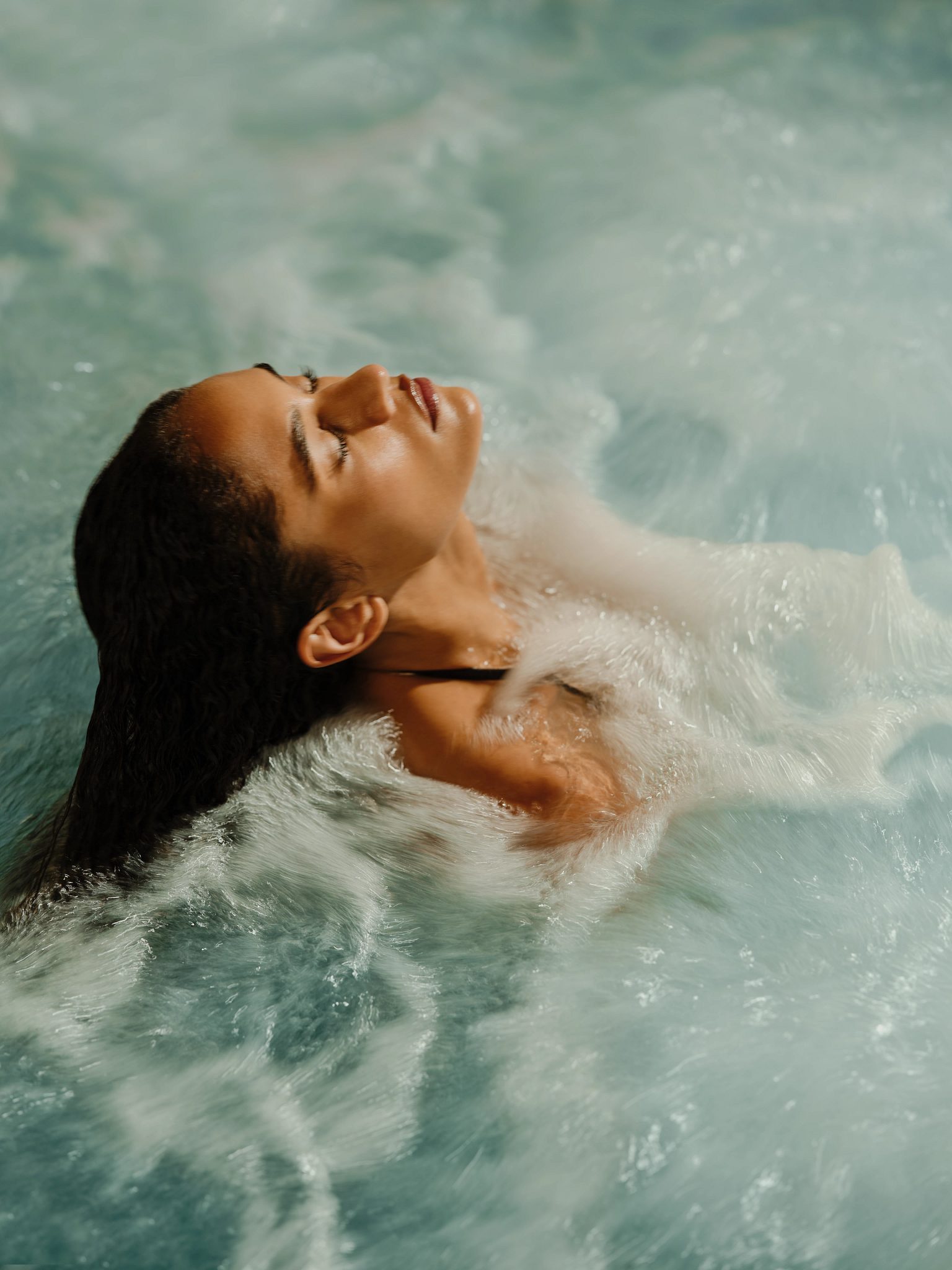 A woman relaxing in a whirpool with her head tilted back