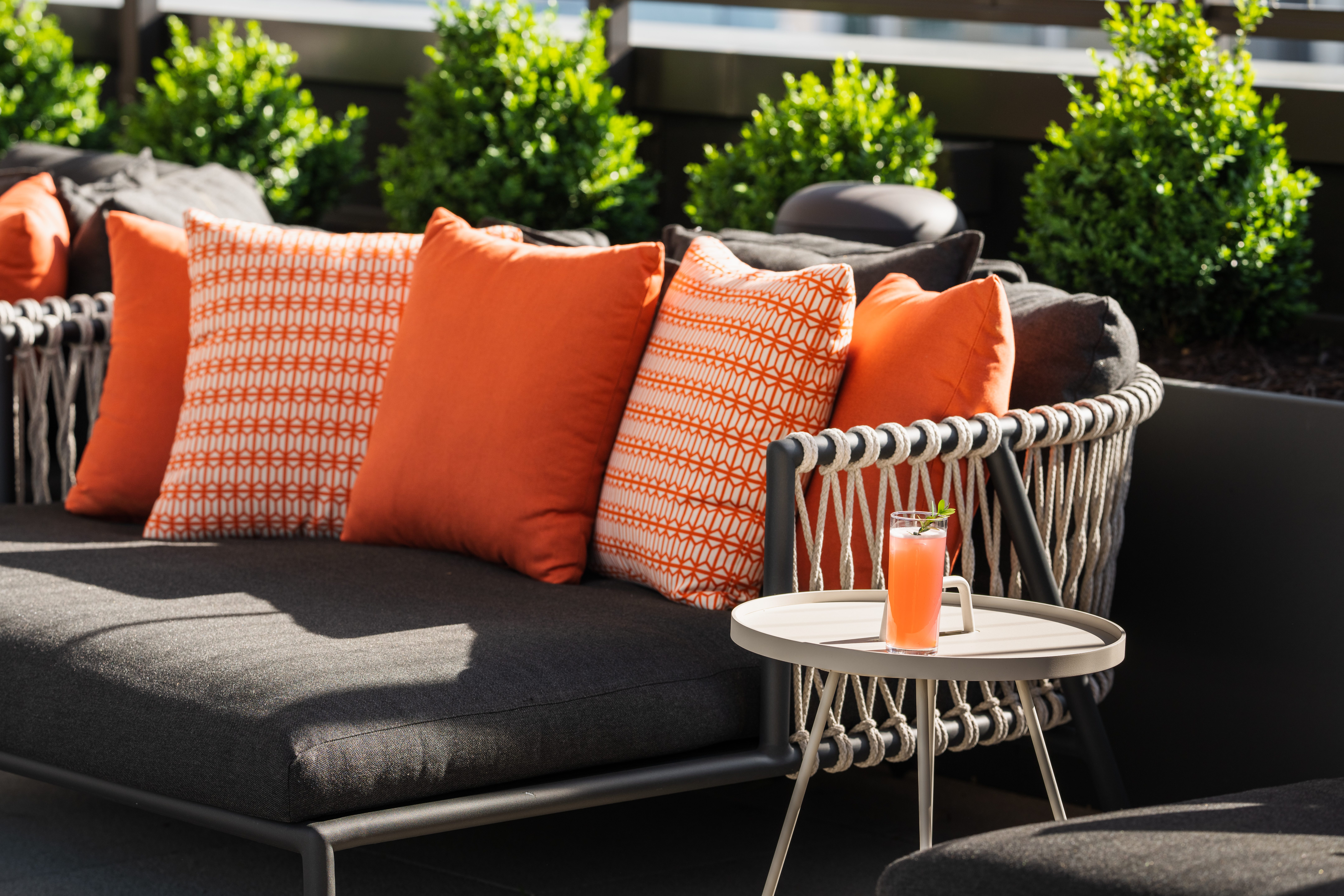 a colorful drink on a small table next to a poolside lounger