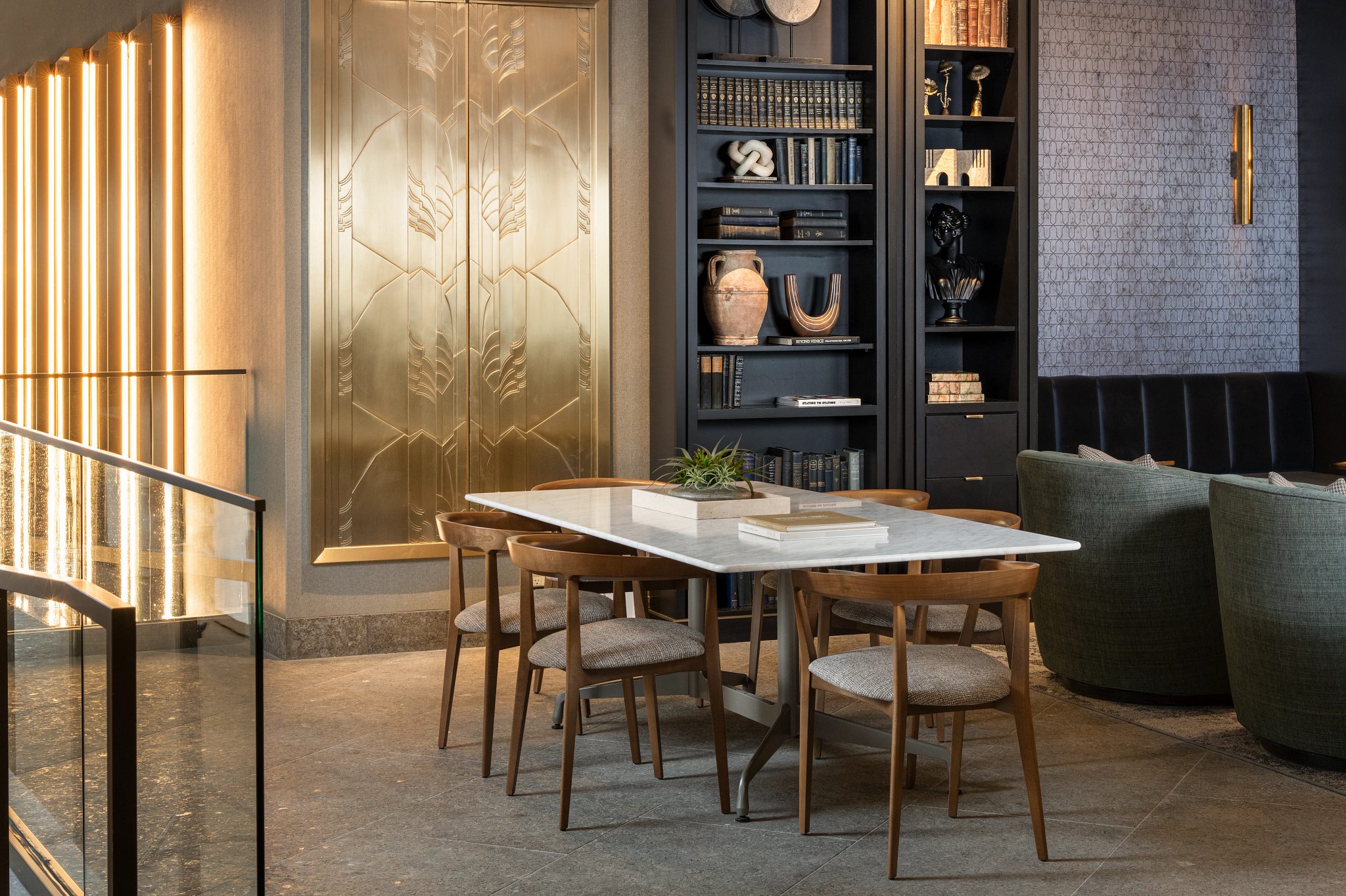 Table and chairs next to a large bookcase and golden wall art