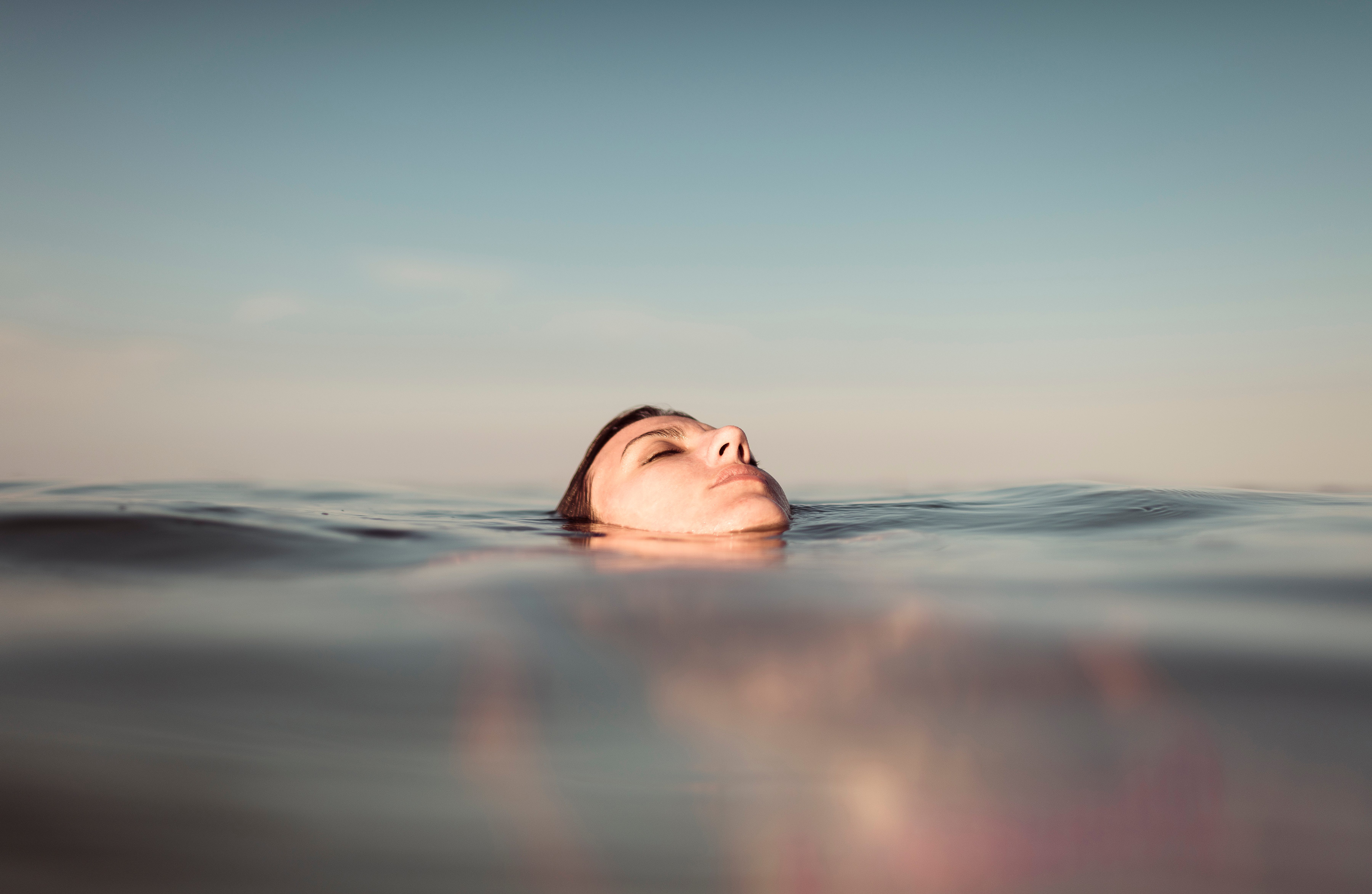 Peaceful portrait of a young beautiful woman floating on the sea and enjoying the relaxed sensation of the moment