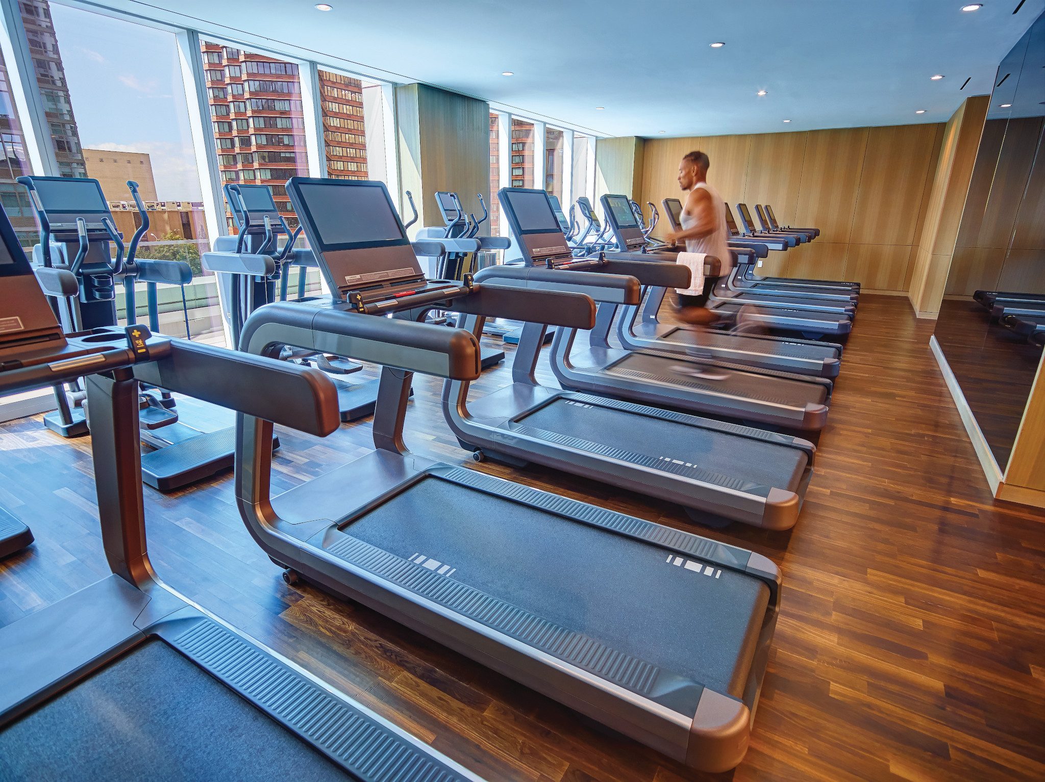 A man running on a treadmill looking through windows onto an urban setting