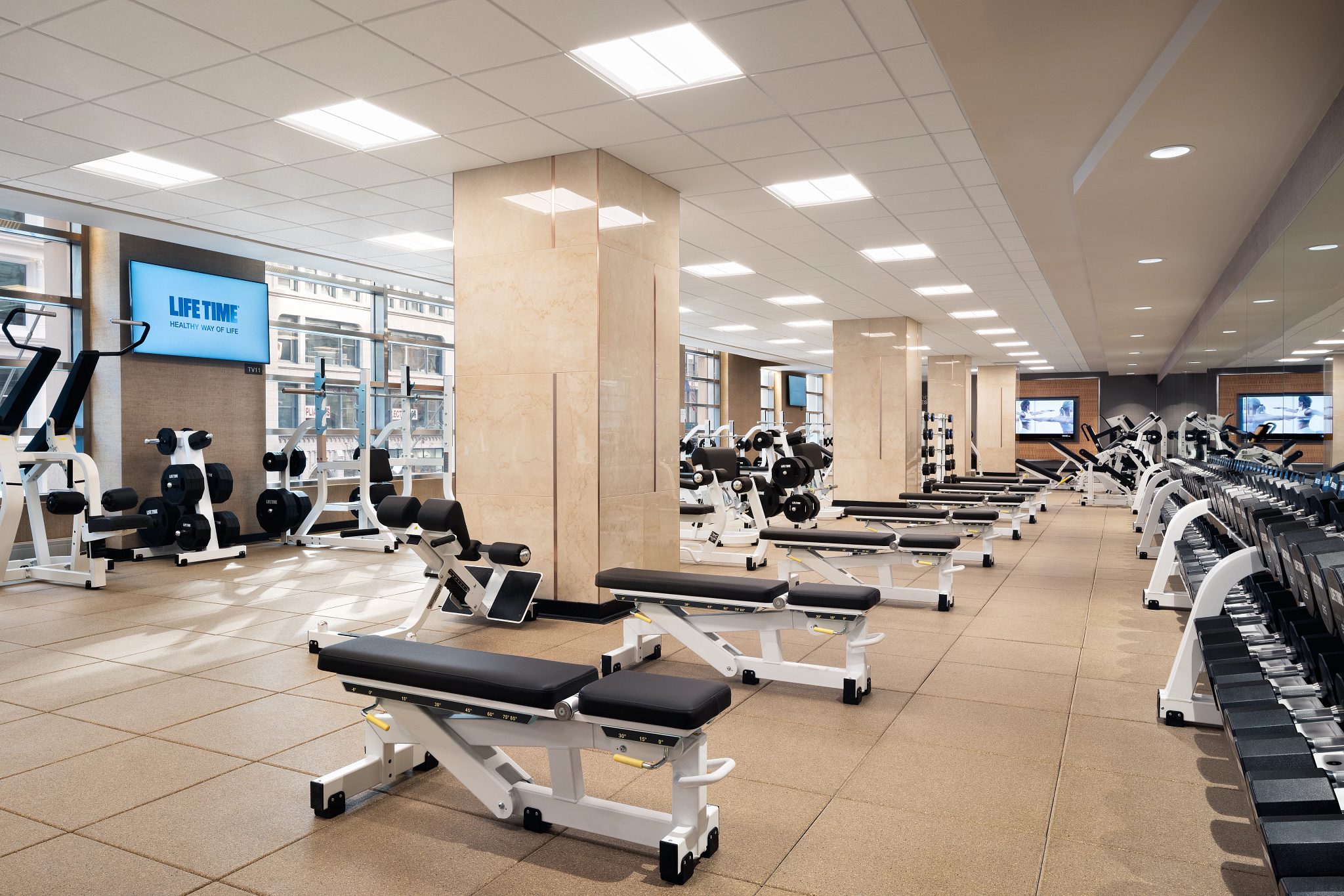 Fitness floor filled with benches and free weights at Life Time