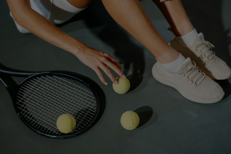 a woman sitting down on the court with a tennis racquet and tennis ball
