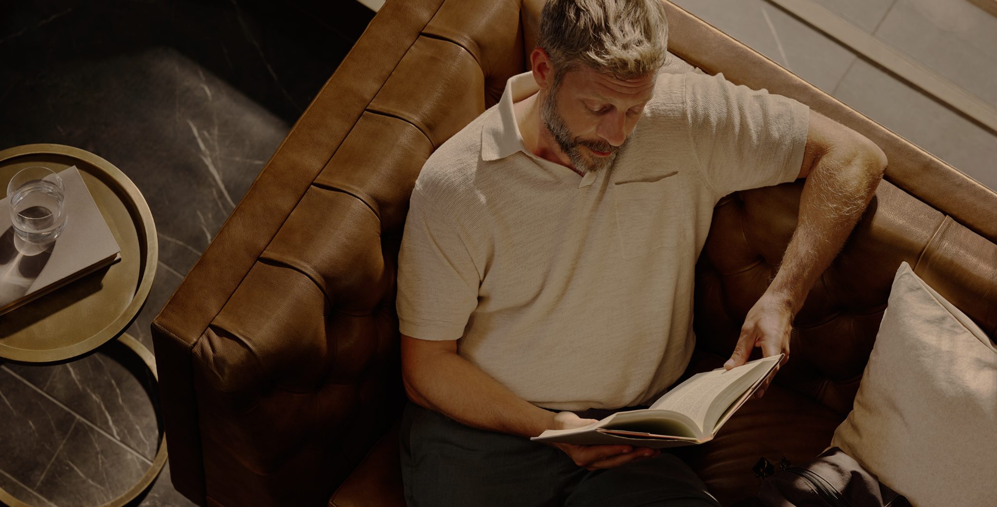 man sitting on a couch reading a book