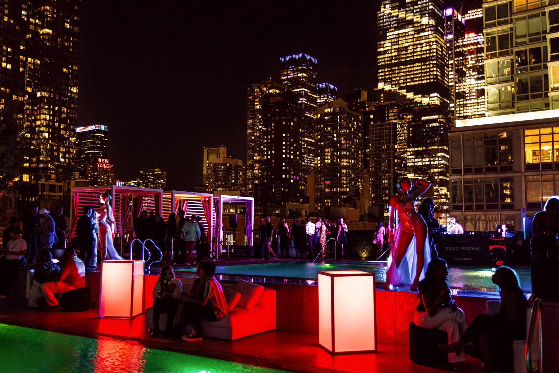 Vibrant rooftop nightlife event with neon-lit installations - modern urban celebration with illuminated structures and skyline views at night.