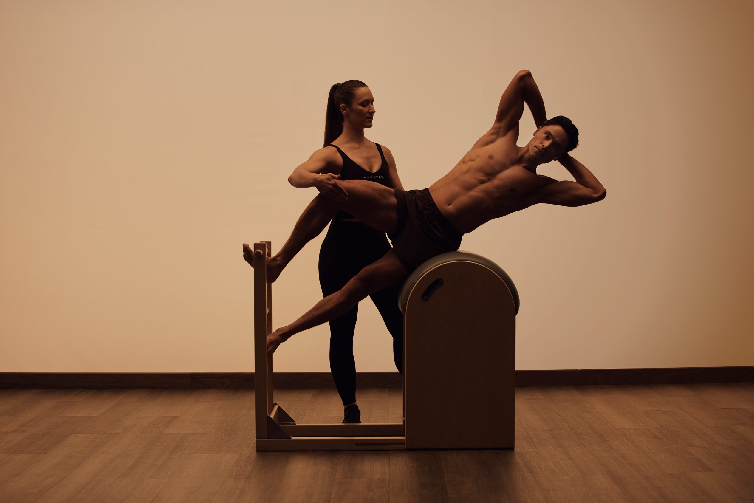 woman helping man doing pilates