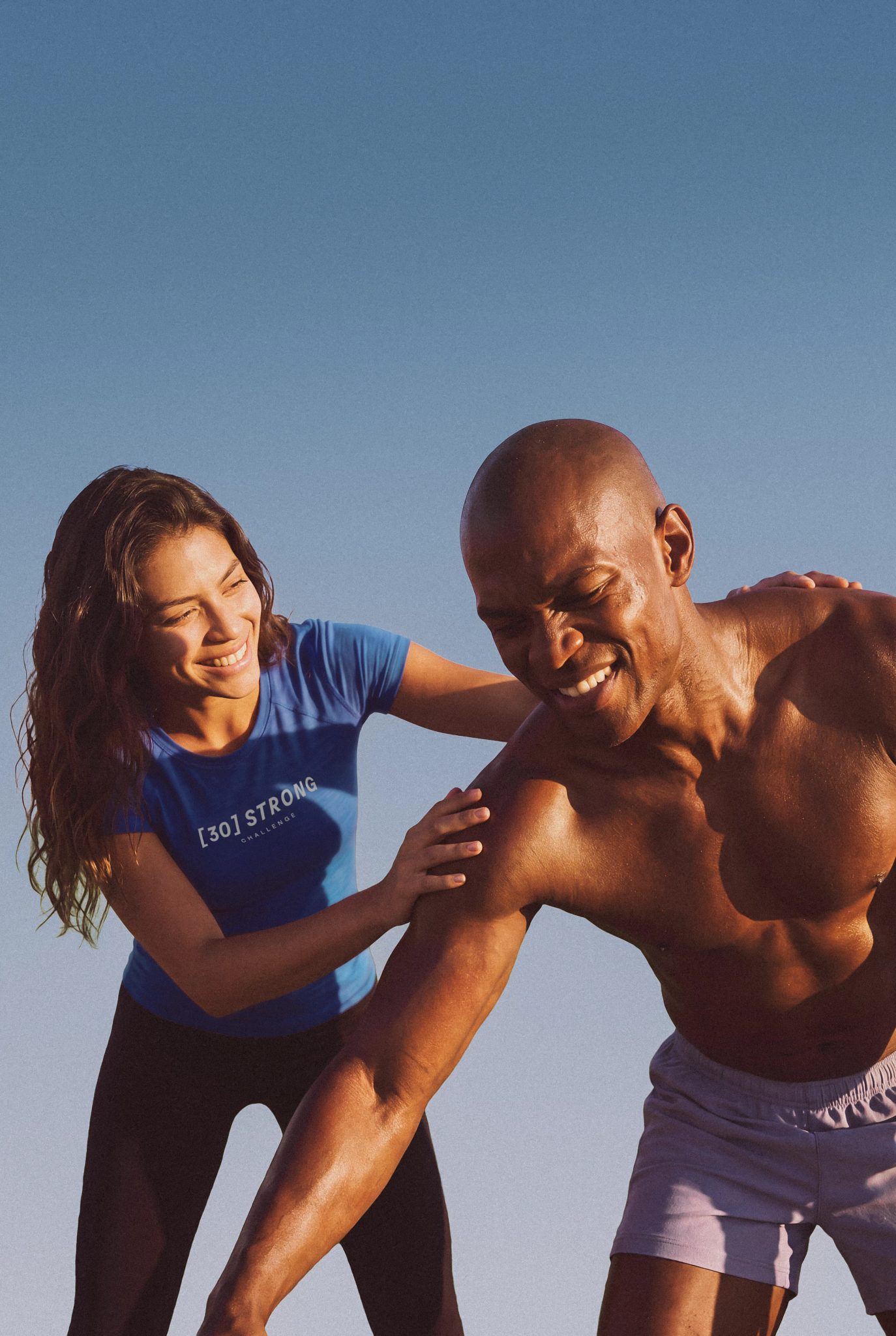 A 30 Strong Dynamic Personal trainer assisting her client during his workout