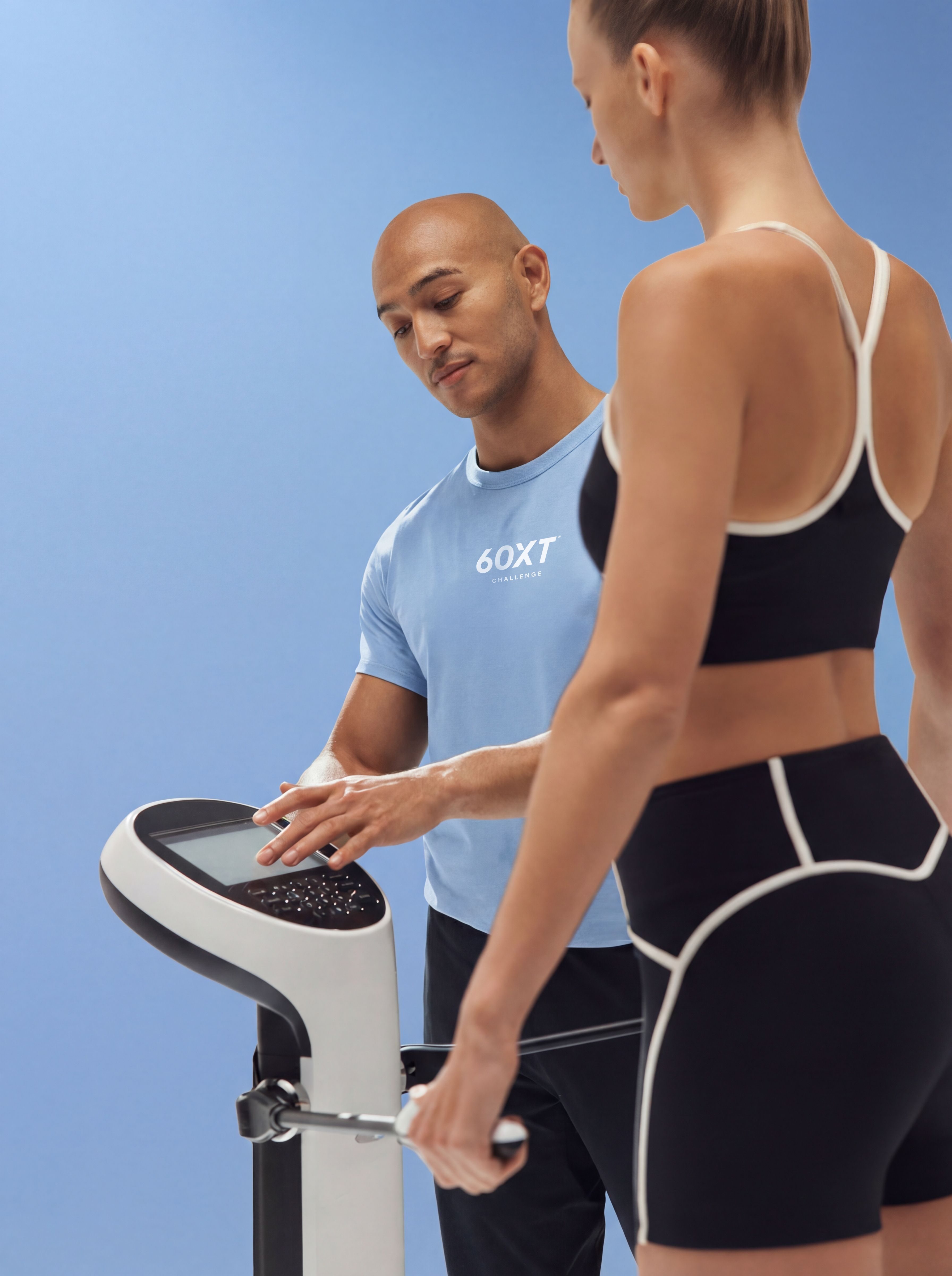 woman standing on a scale while trainer measures her weight