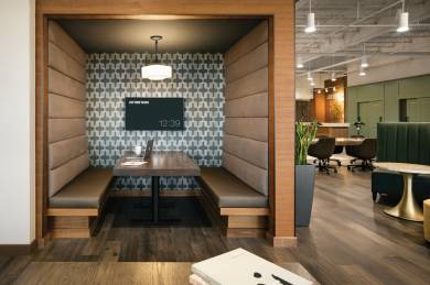 A Life Time workspace with a wooden floor, tables and a booth with cushioned benches