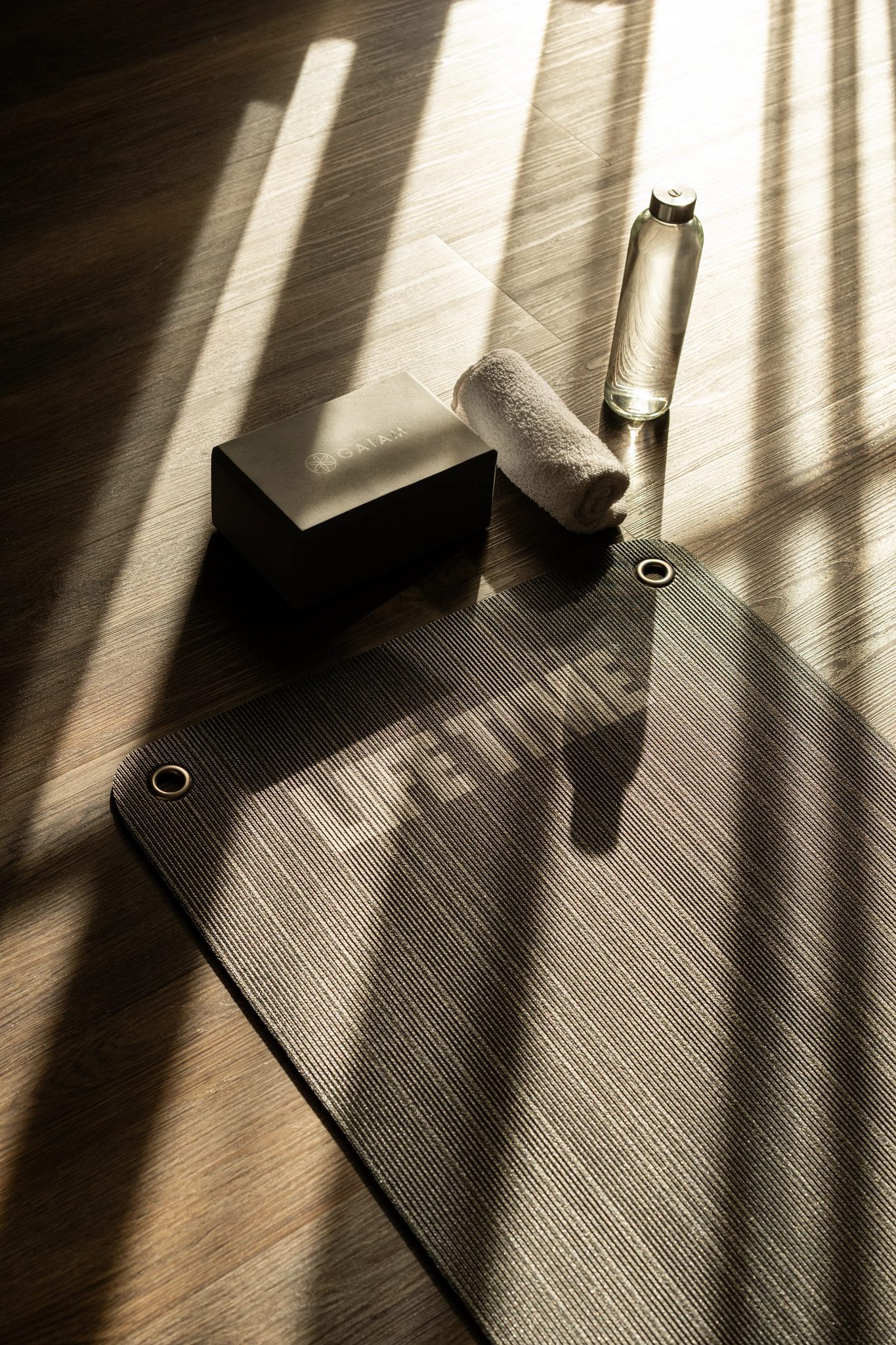 a yoga mat with a block, towel and water bottle