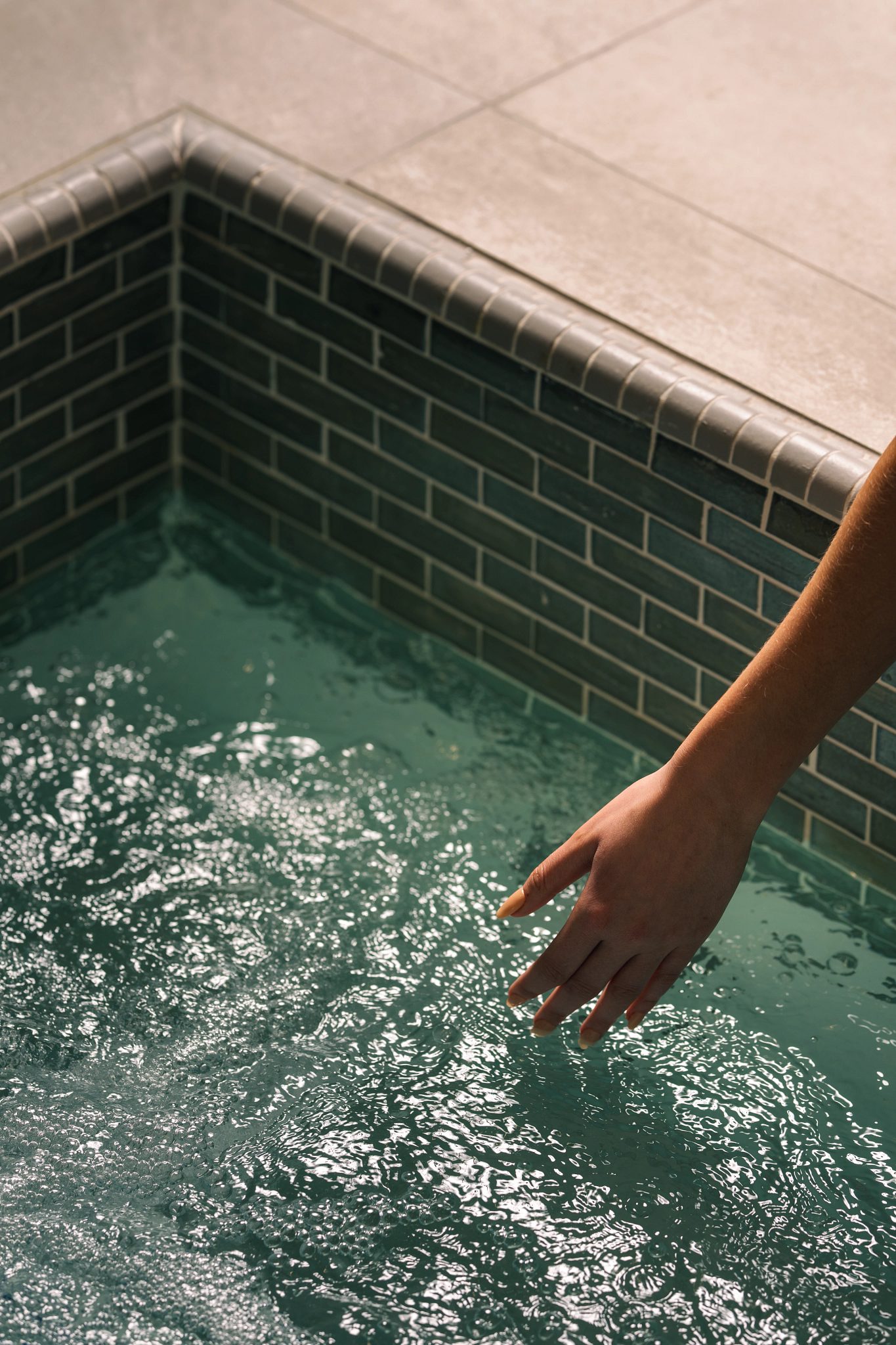A female hand reaching into the water in a whirlpool
