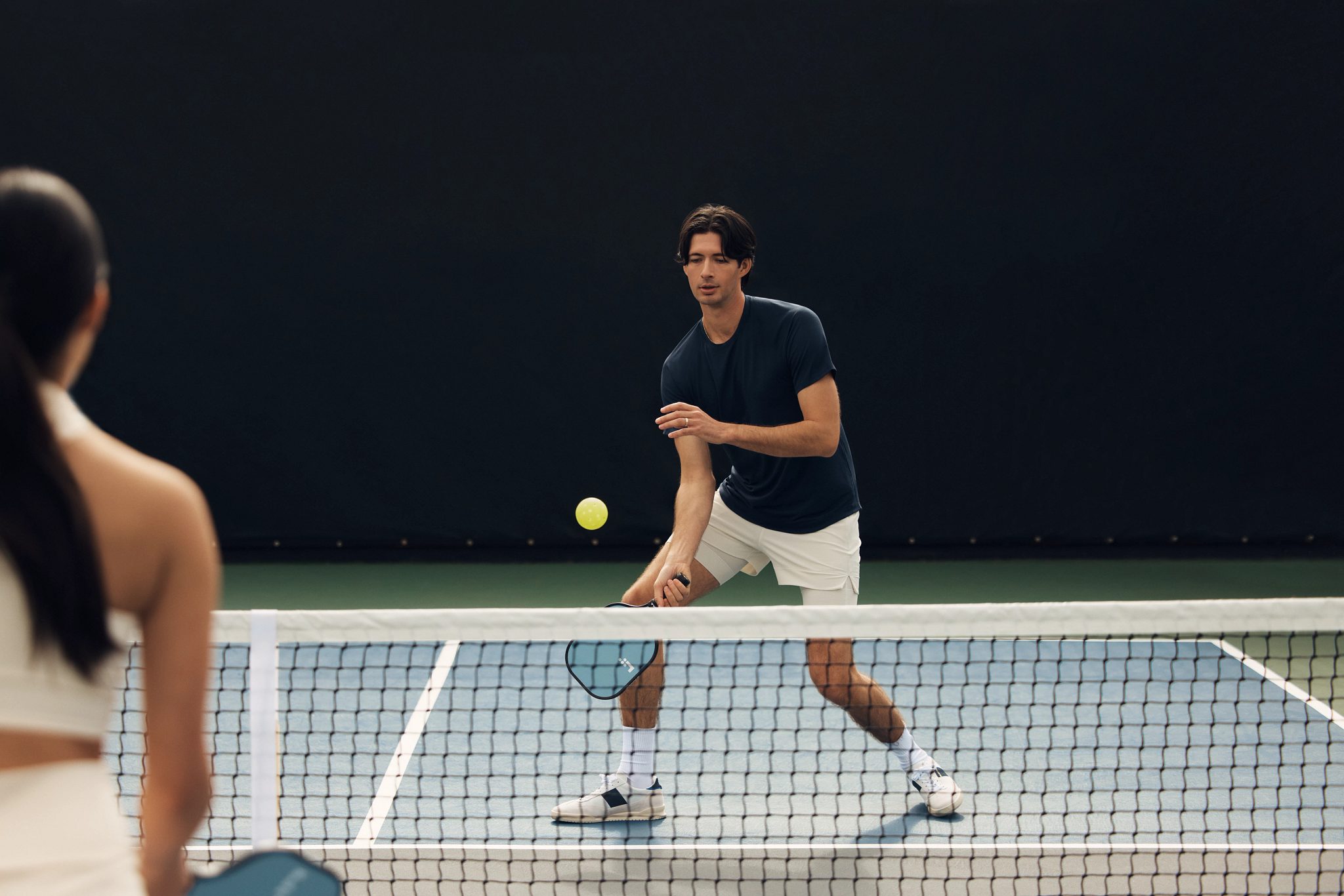 A pickleball player dinking over the net during a game at Life Time