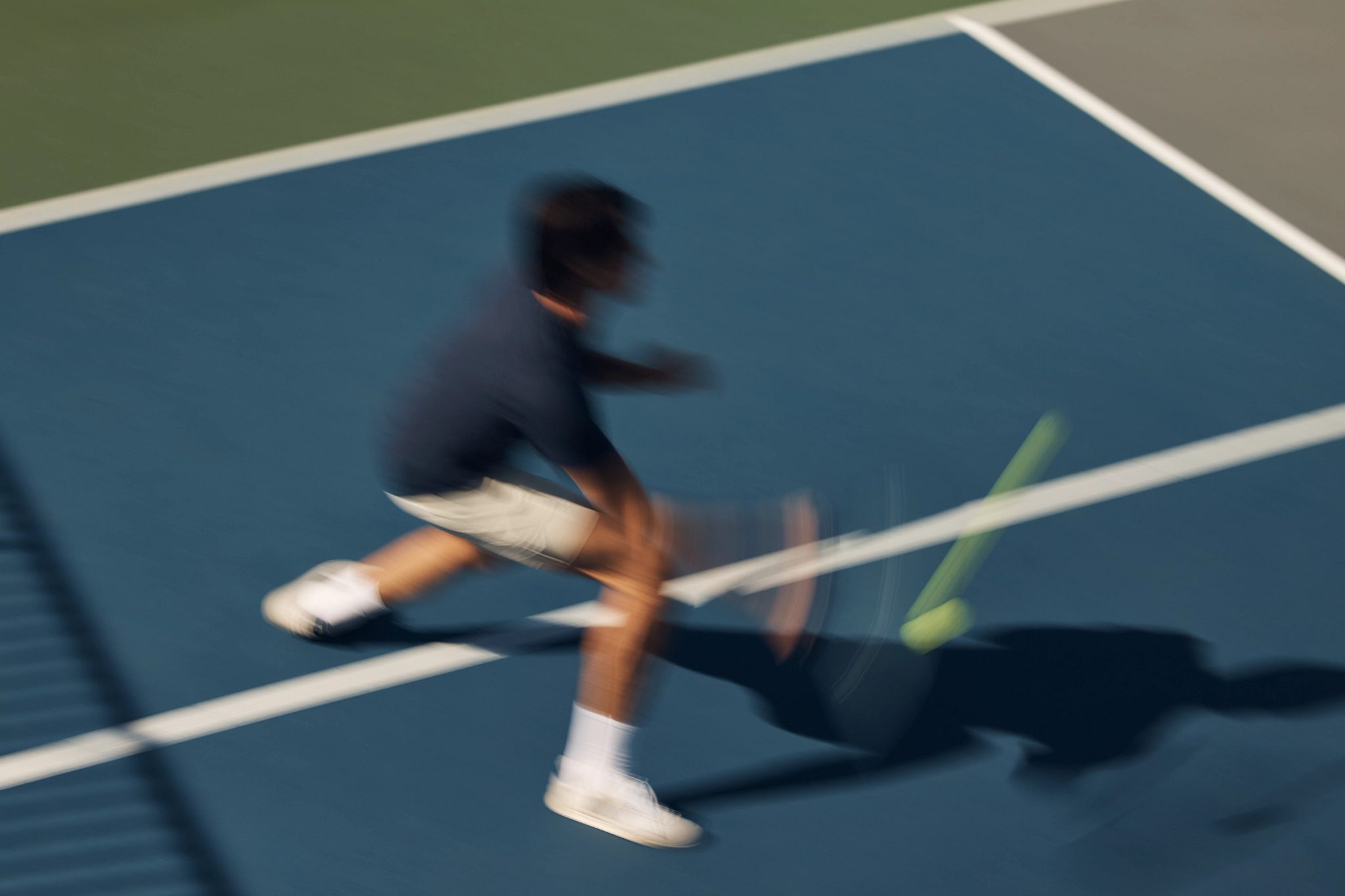 Stylized blurred image of a pickball player swinging at a pickleball