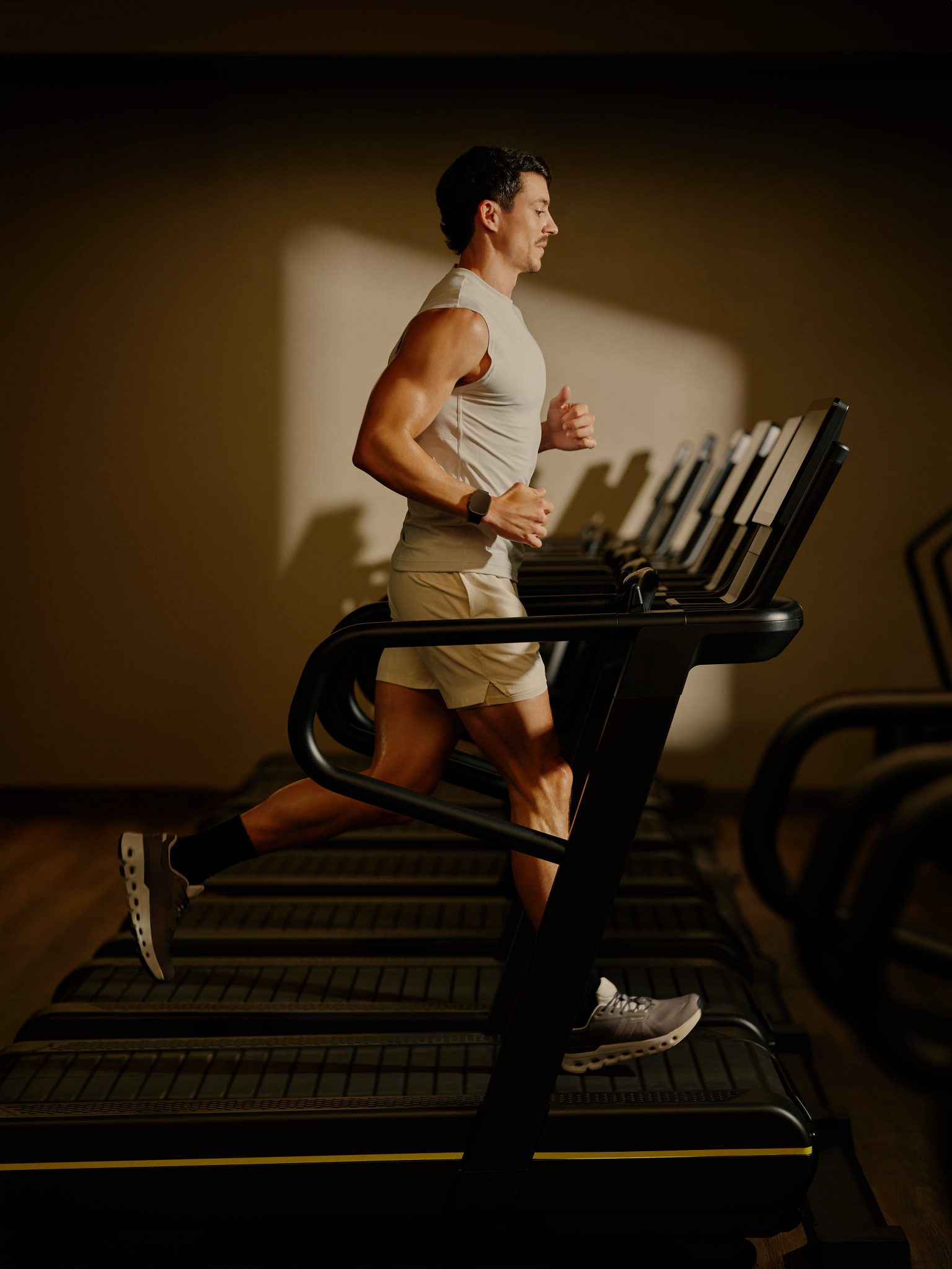 A man running on a treadmill in a dimly lit room