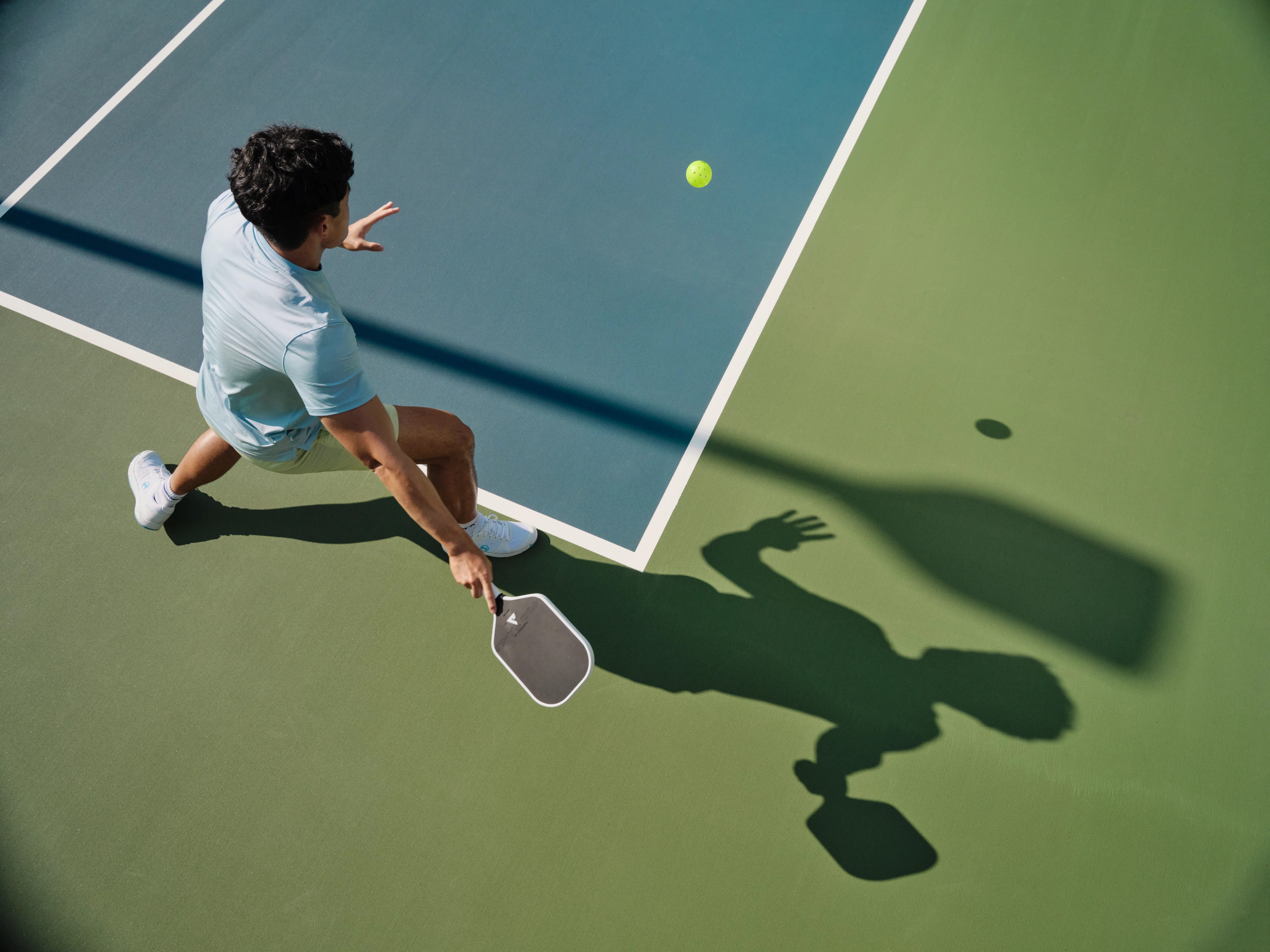 Closeup of a pickleball player on an outdoor court about to hit the ball