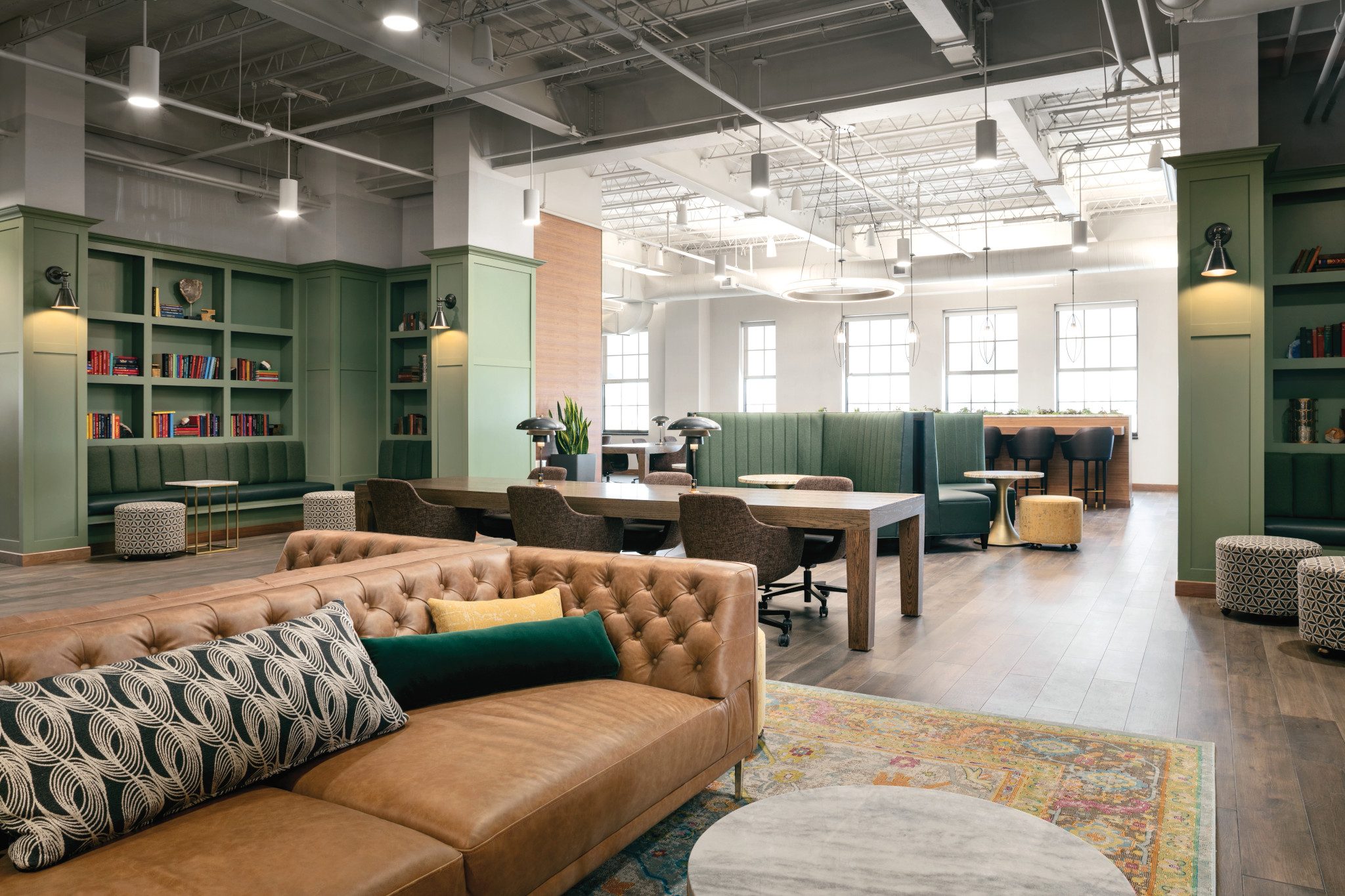 A brightly lit office area with sofas, wooden tables and chairs at Life Time Work Ardmore