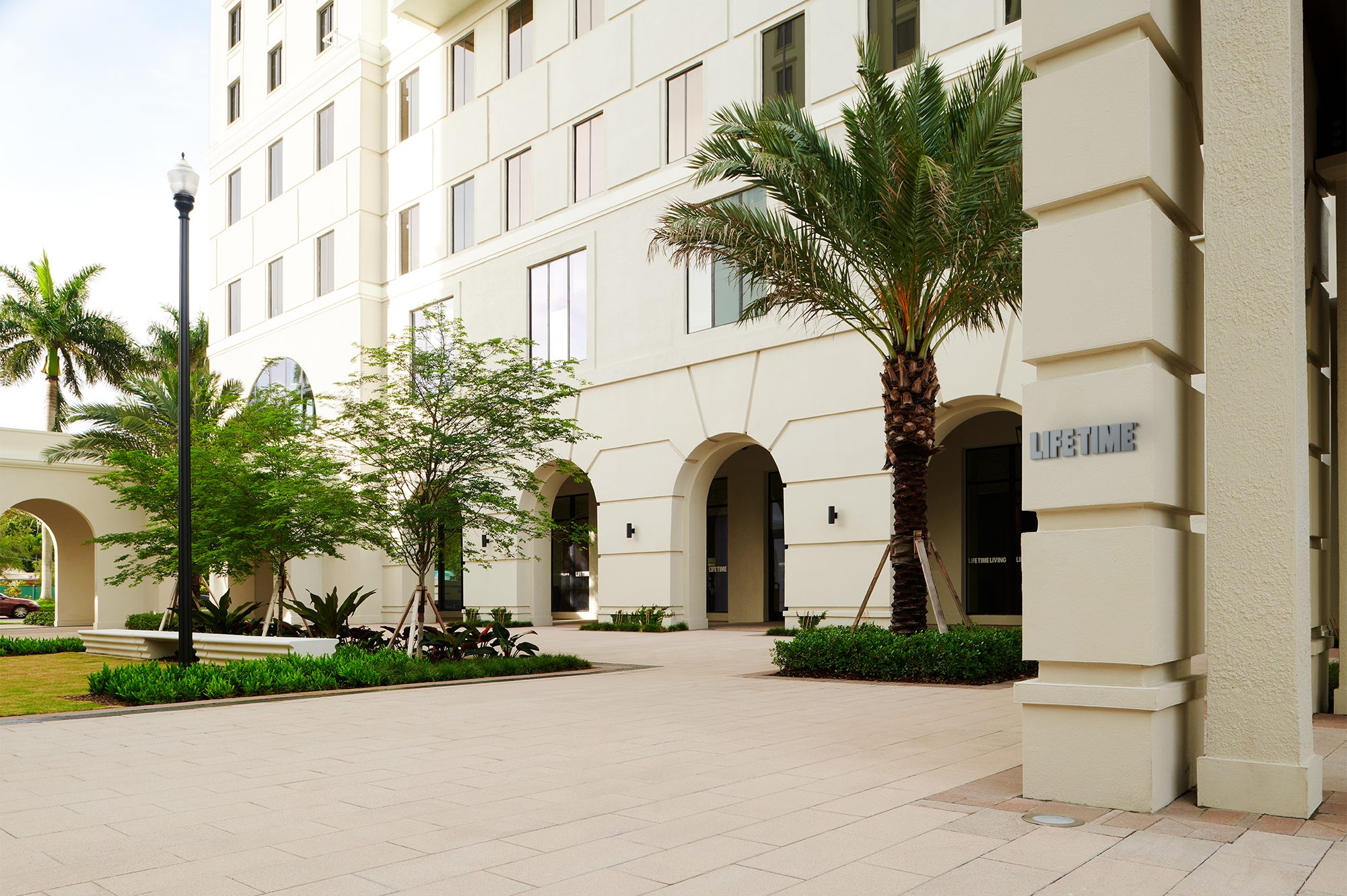 Exterior courtyard filled with greenery and palm trees outside of Life Time Coral Gables