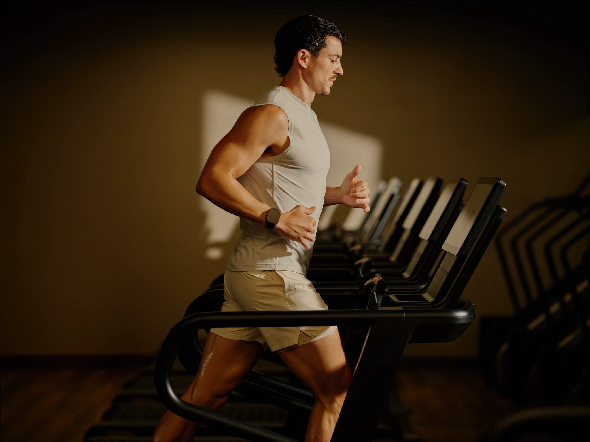 A man running on a treadmill in a dimly lit room