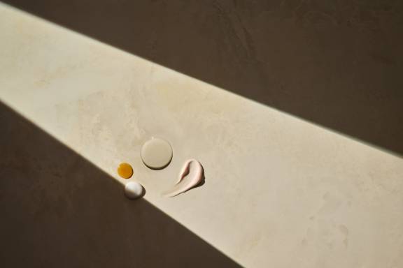 A variety of oils and lotions smeared on top of a cream marbled countertop